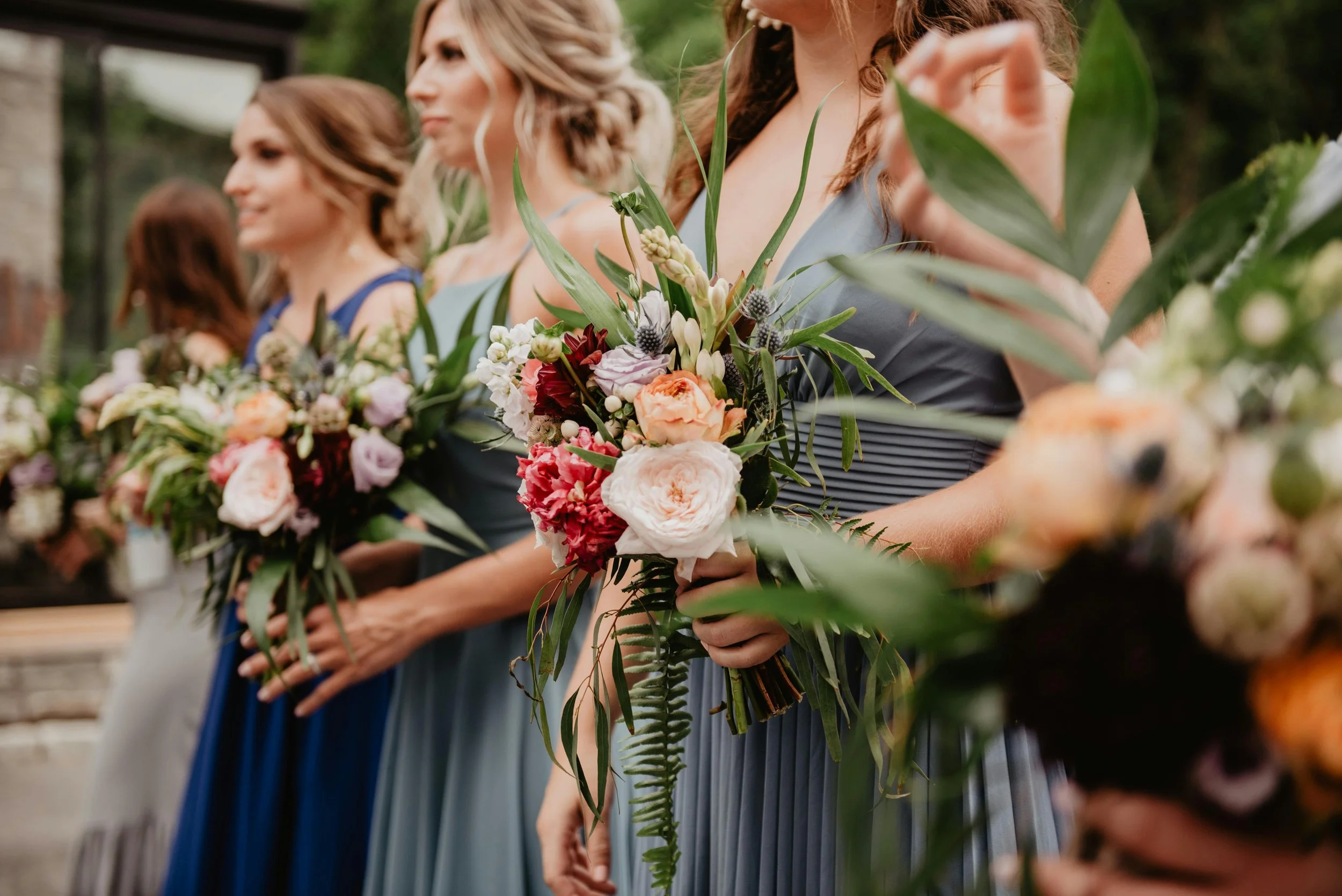 bridesmaids stood together holding big bouquets