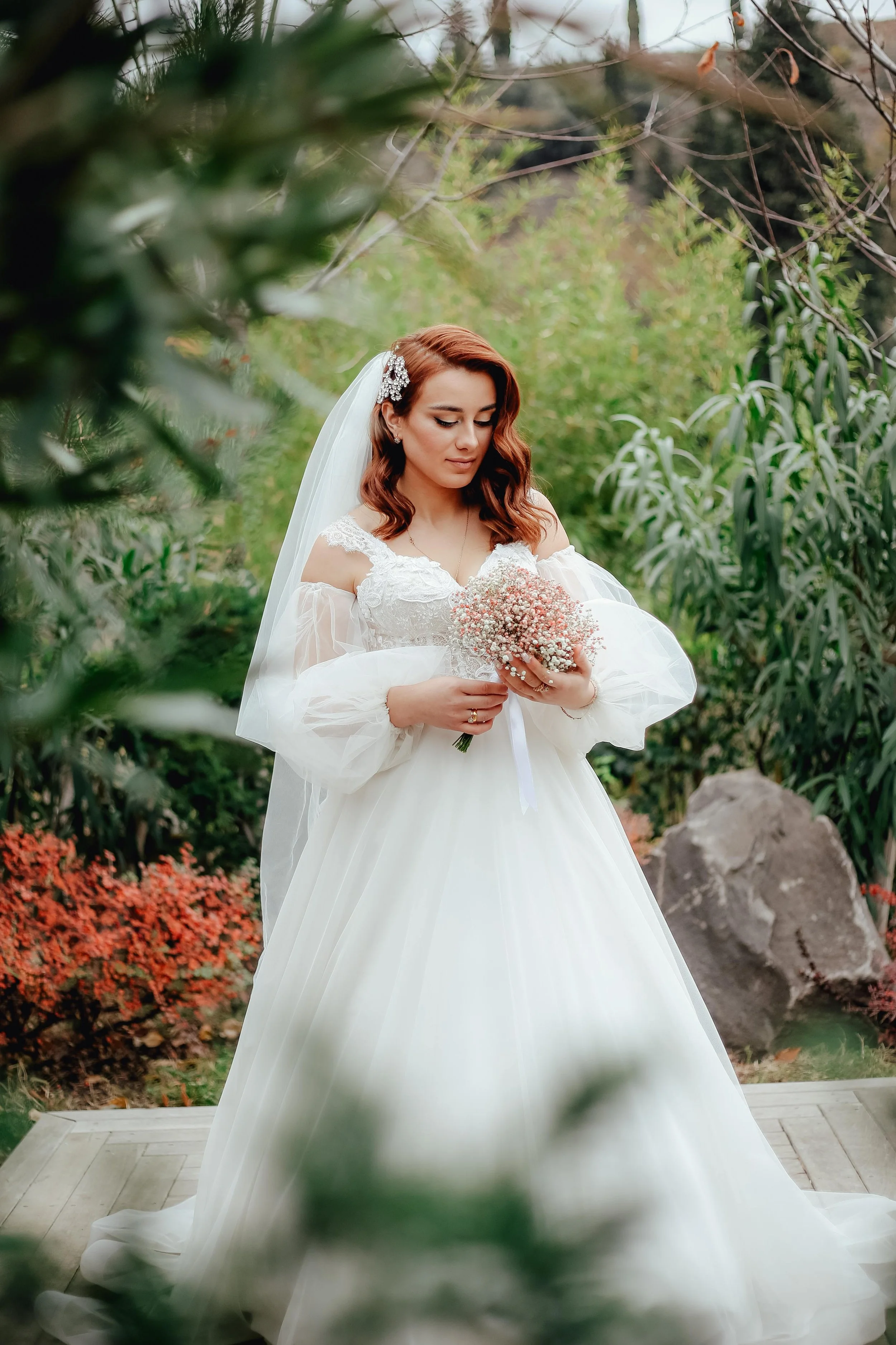 Bride stood having her photo taken looking down at her wedding bouquet