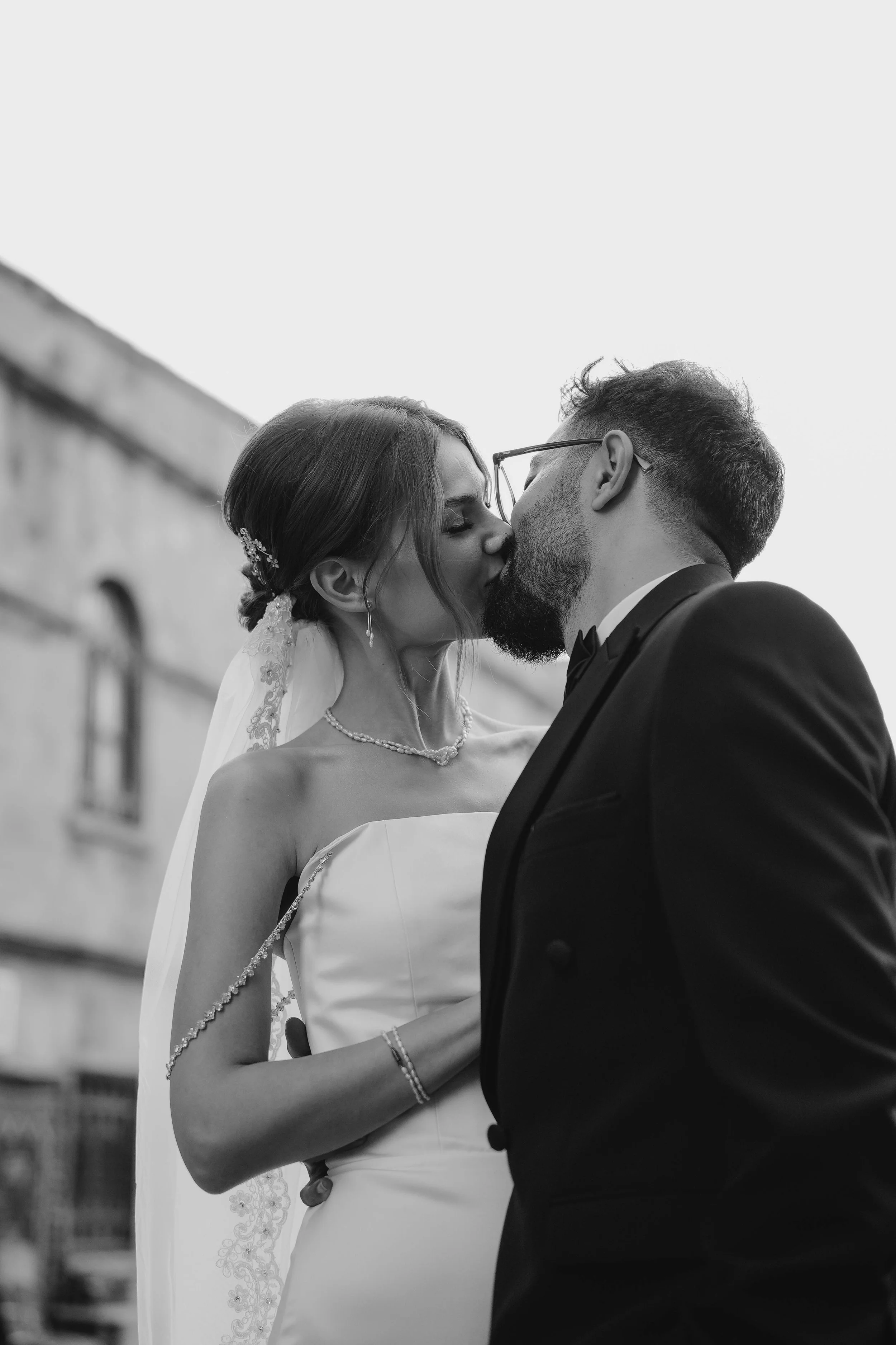 black and white photo of bride and groom kissing after ceremony
