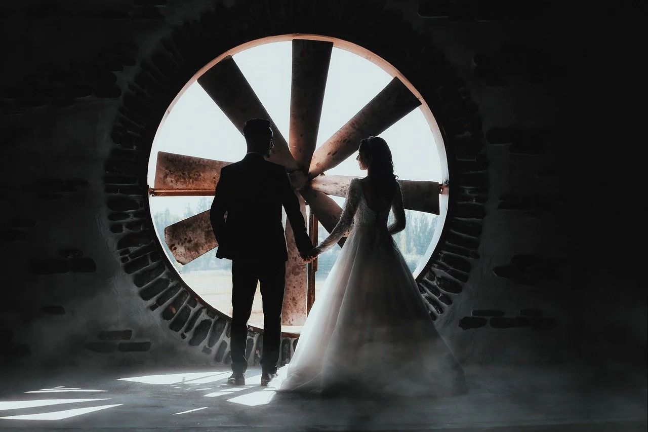 bride and groom together looking out of old mill window