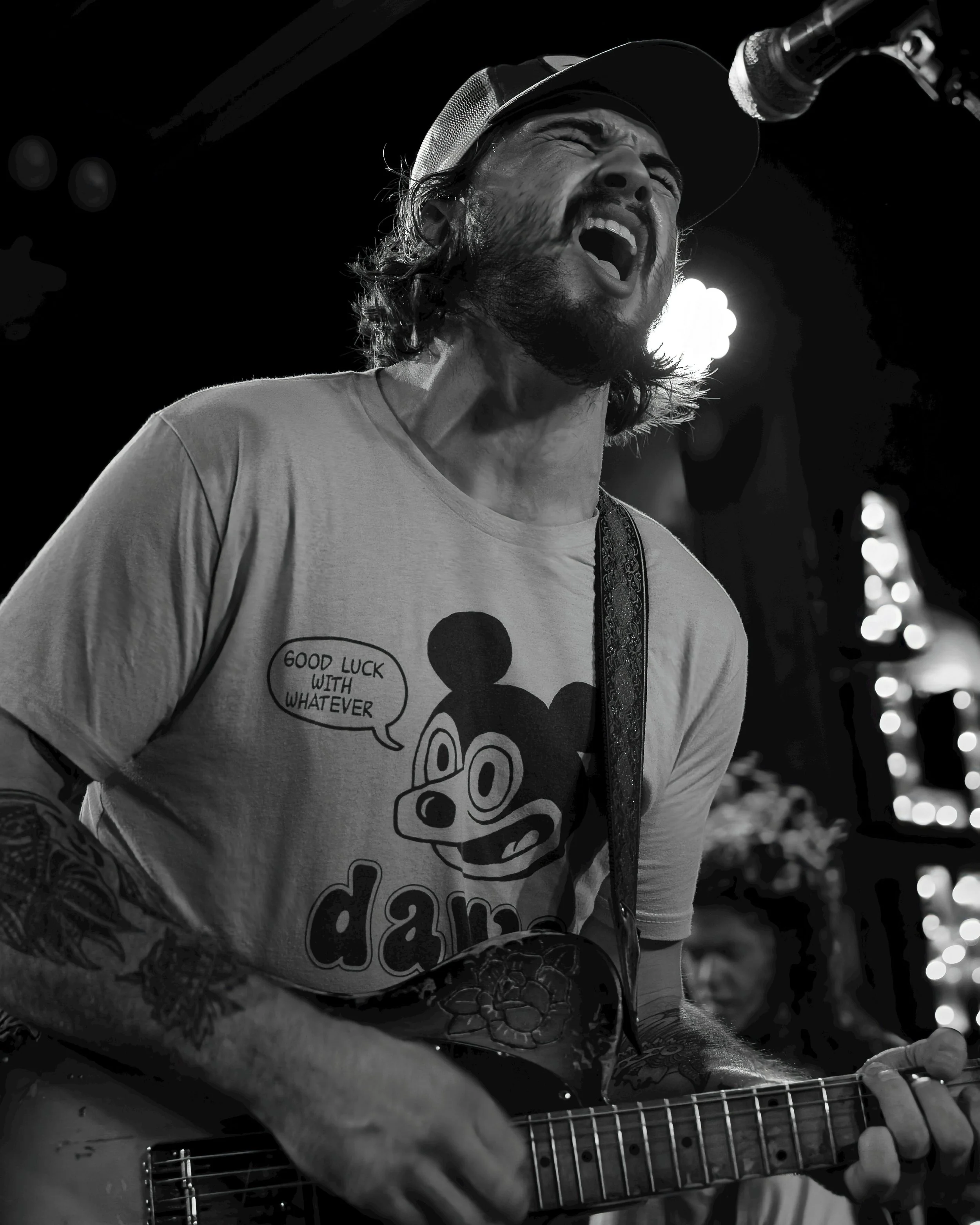 black and white image of singer on stage playing the guitar