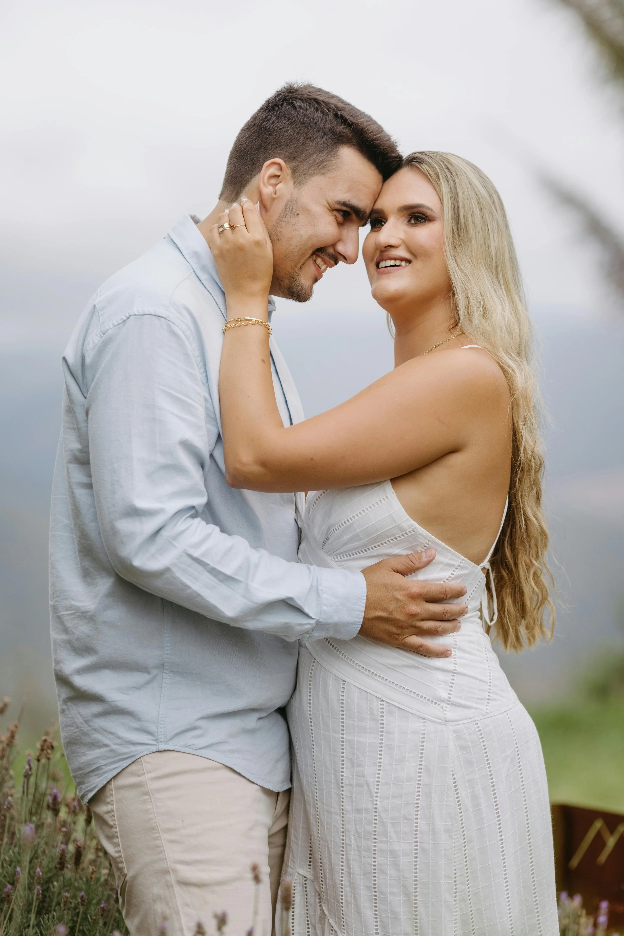 Newley engaged couple in a field looking happy holding each other