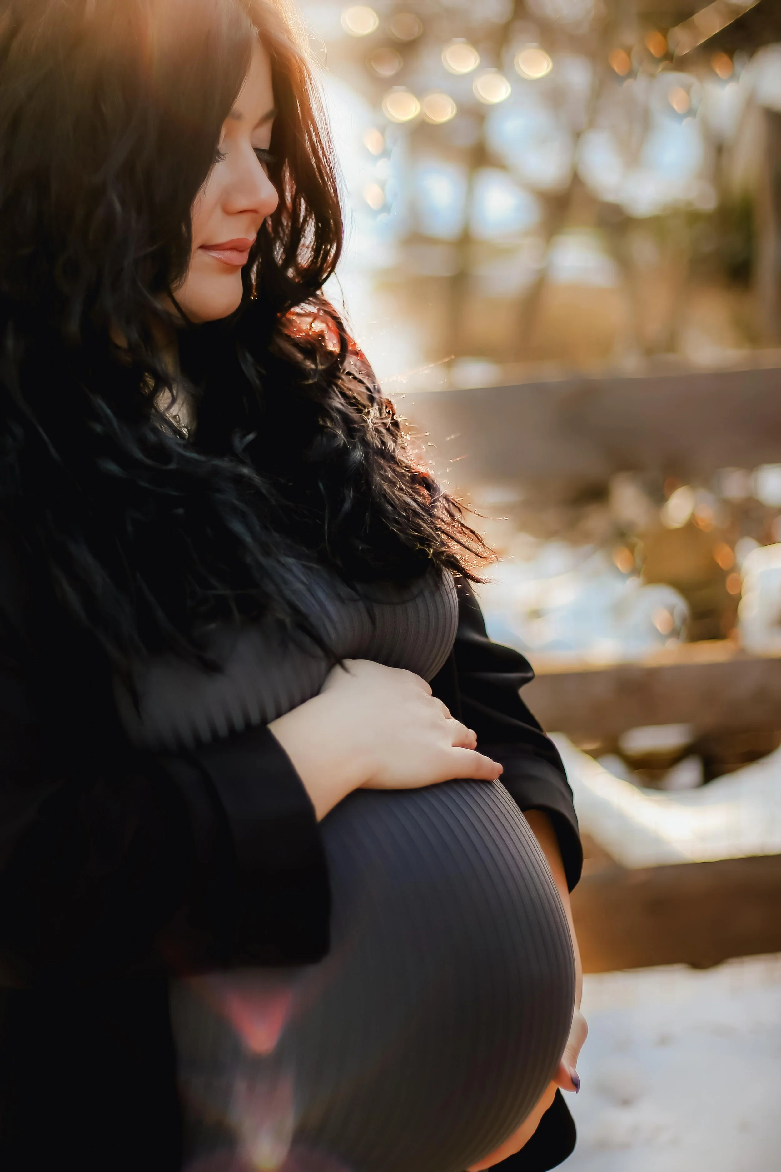 expecting mother holding her tummy in the autumn sunlight