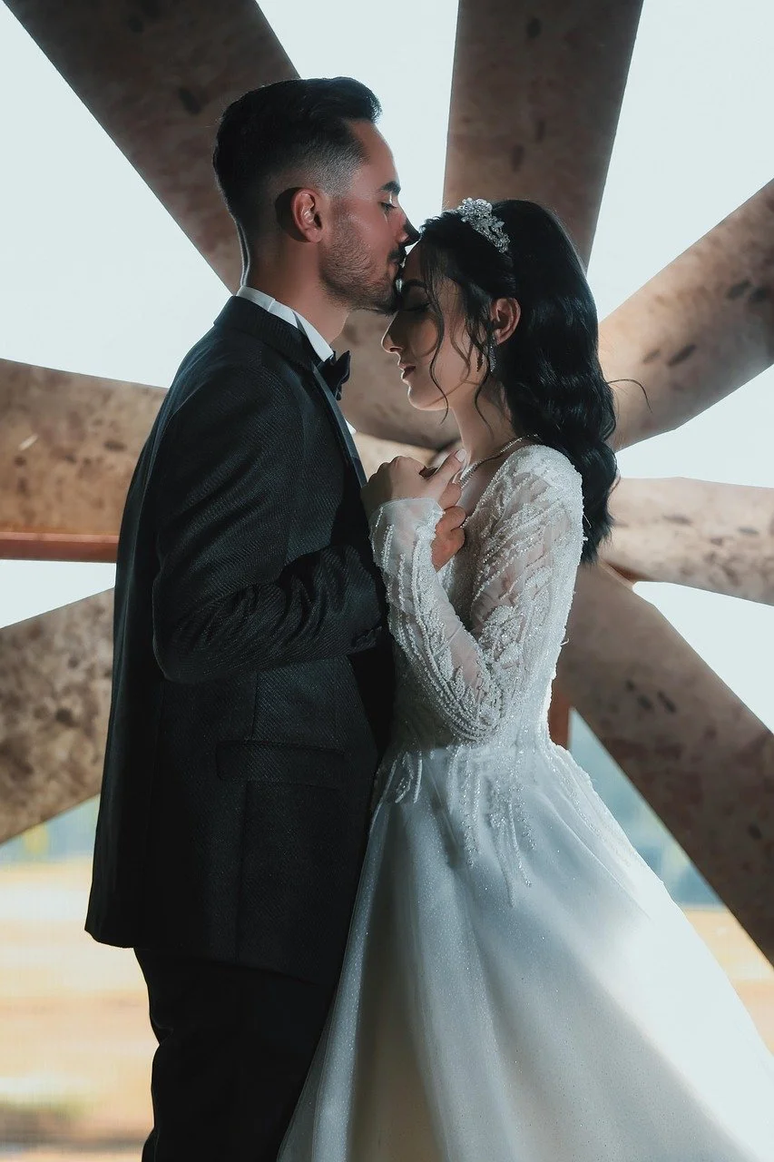 groom kisses brides forehead as they stand facing each other
