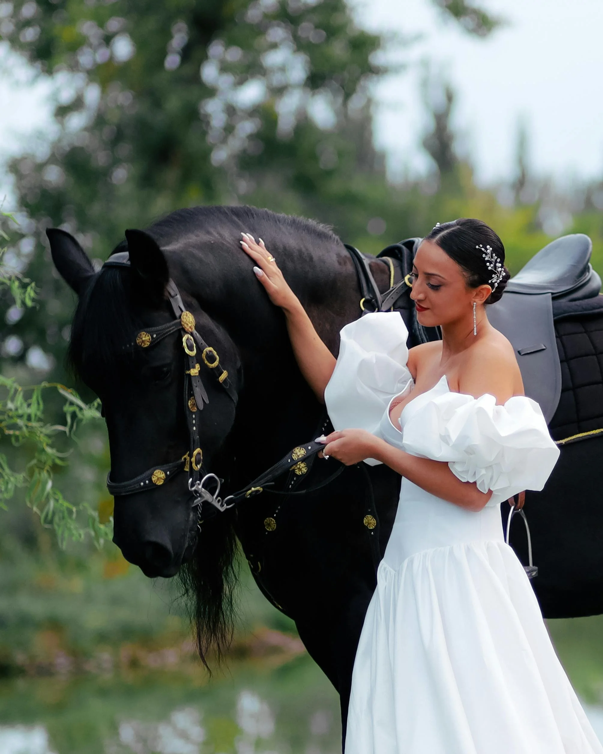 bride looking at black Friesian stallion with one hand on his neck