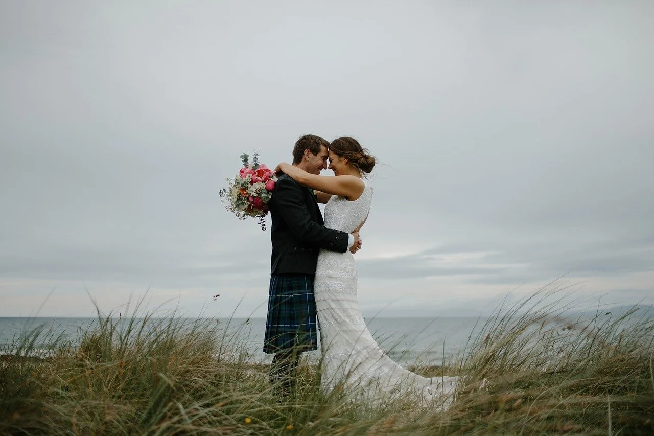 bride and groom together holding each other on the dunes
