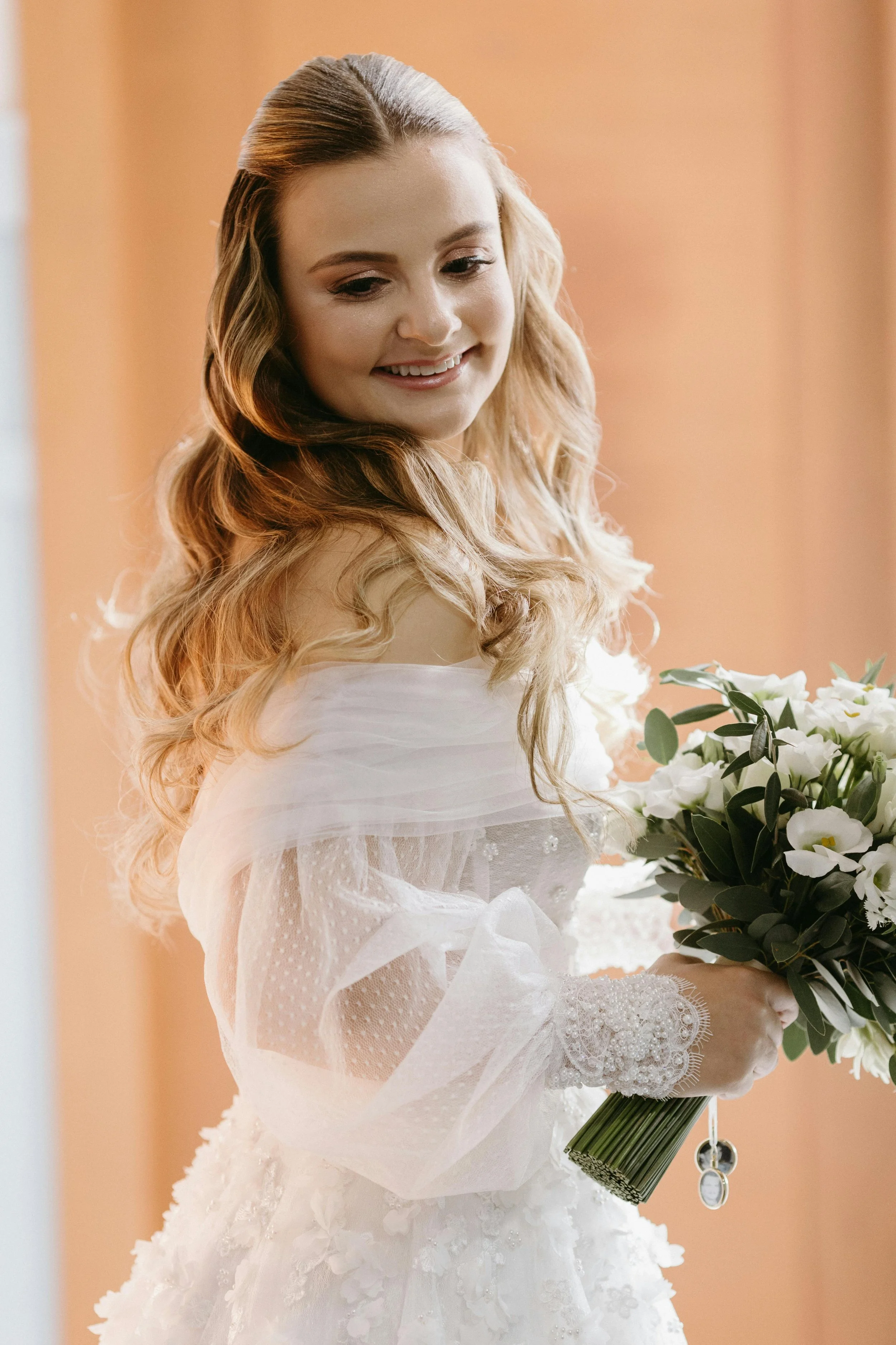 bride stood in hallway looking down holding her wedding flowers