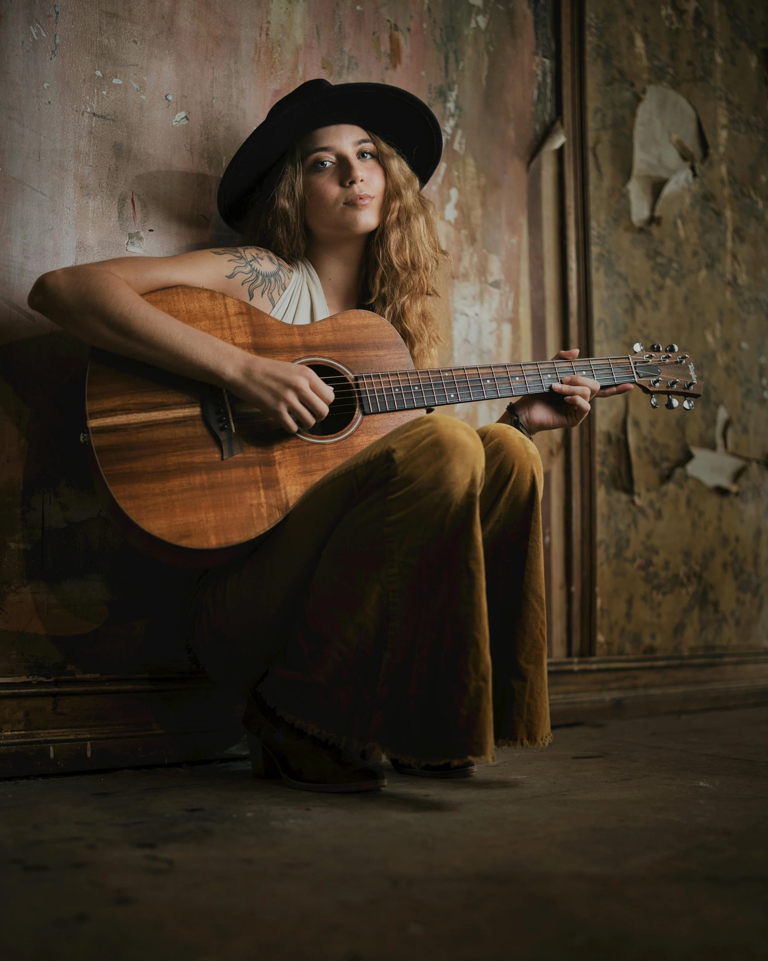 female singer sat against urban background with guitar