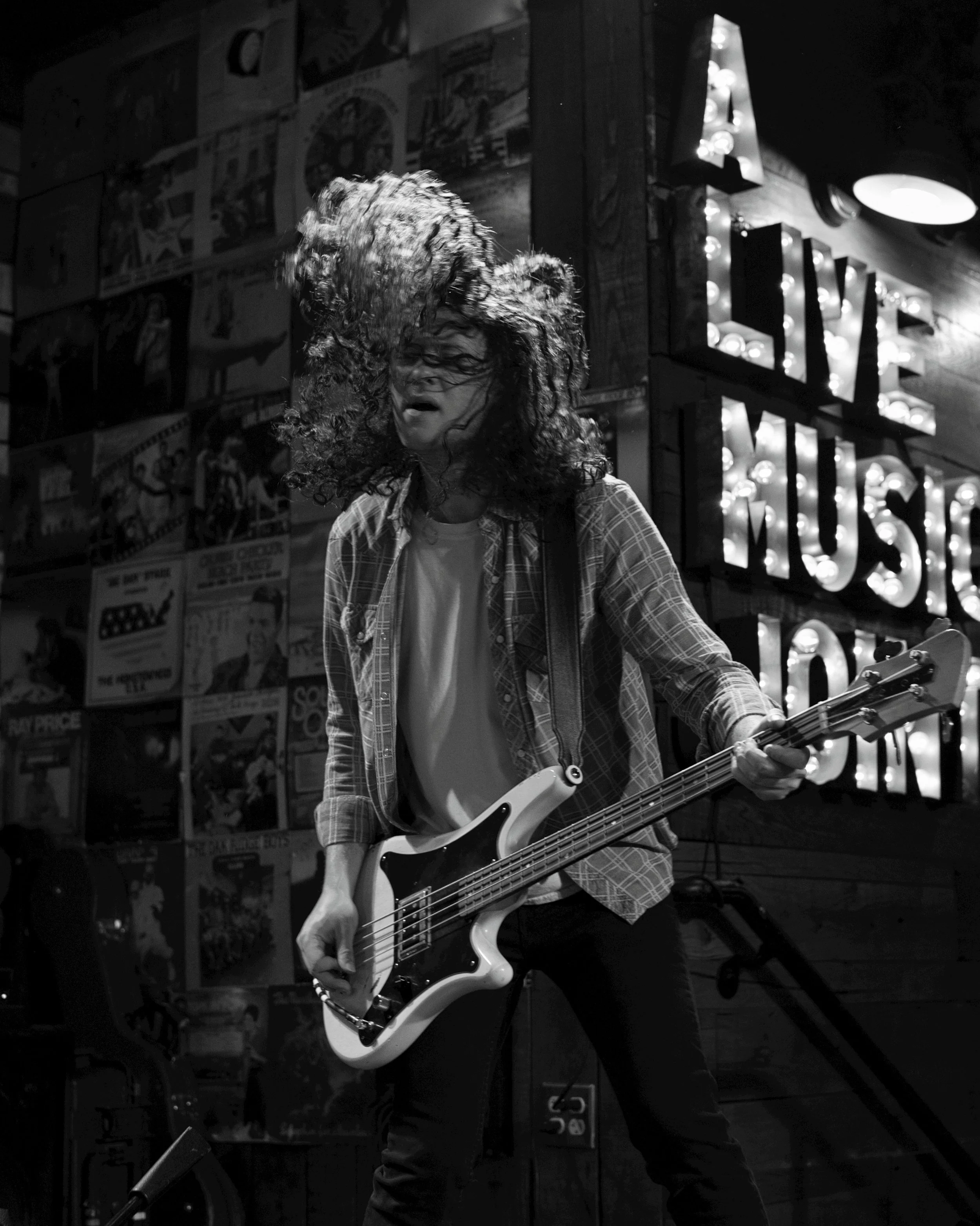 black and white image of long haired base player on stage in live performance