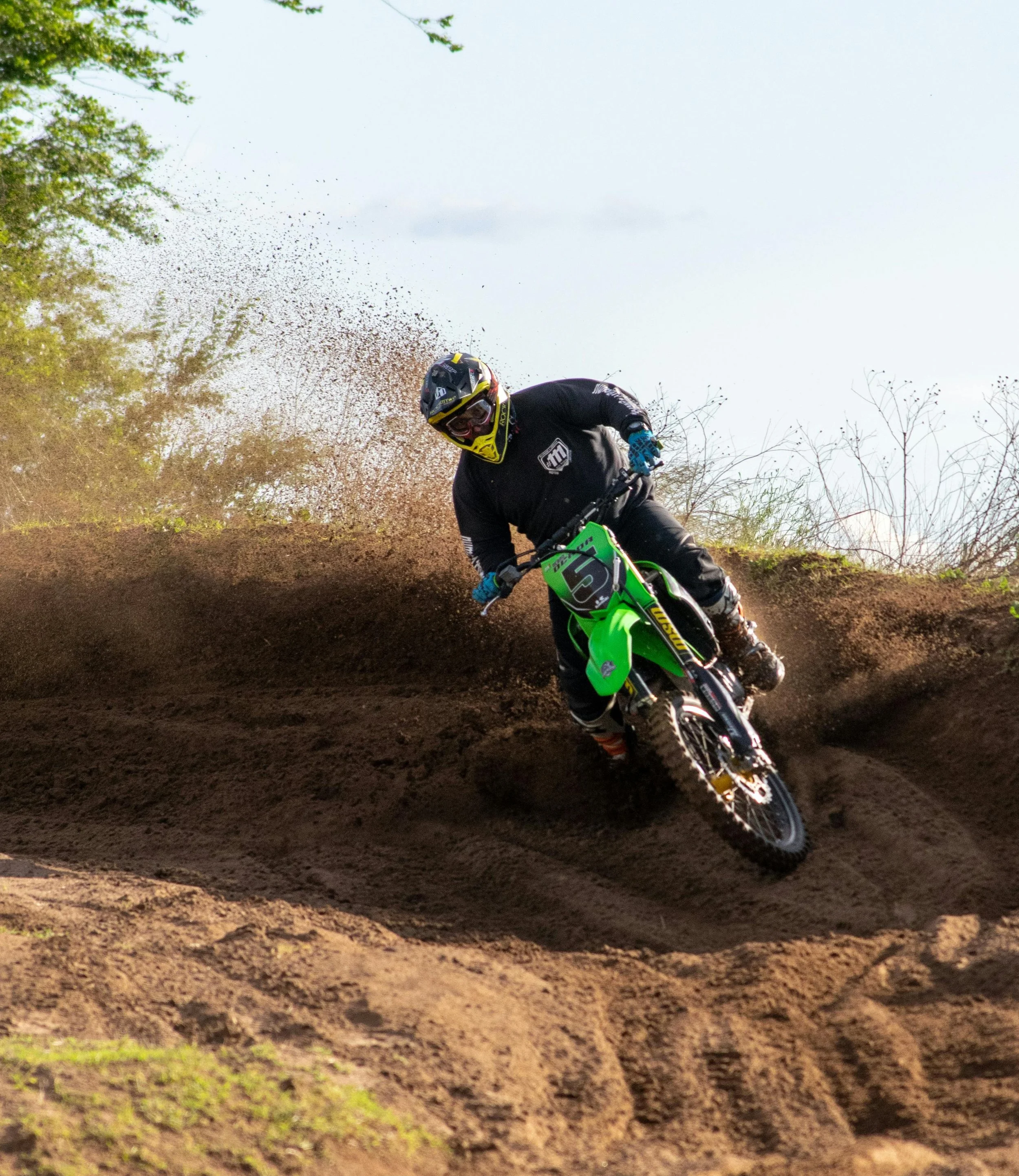 motocross rider coming over the hill and down the dirt track kicking up some dirt behind them