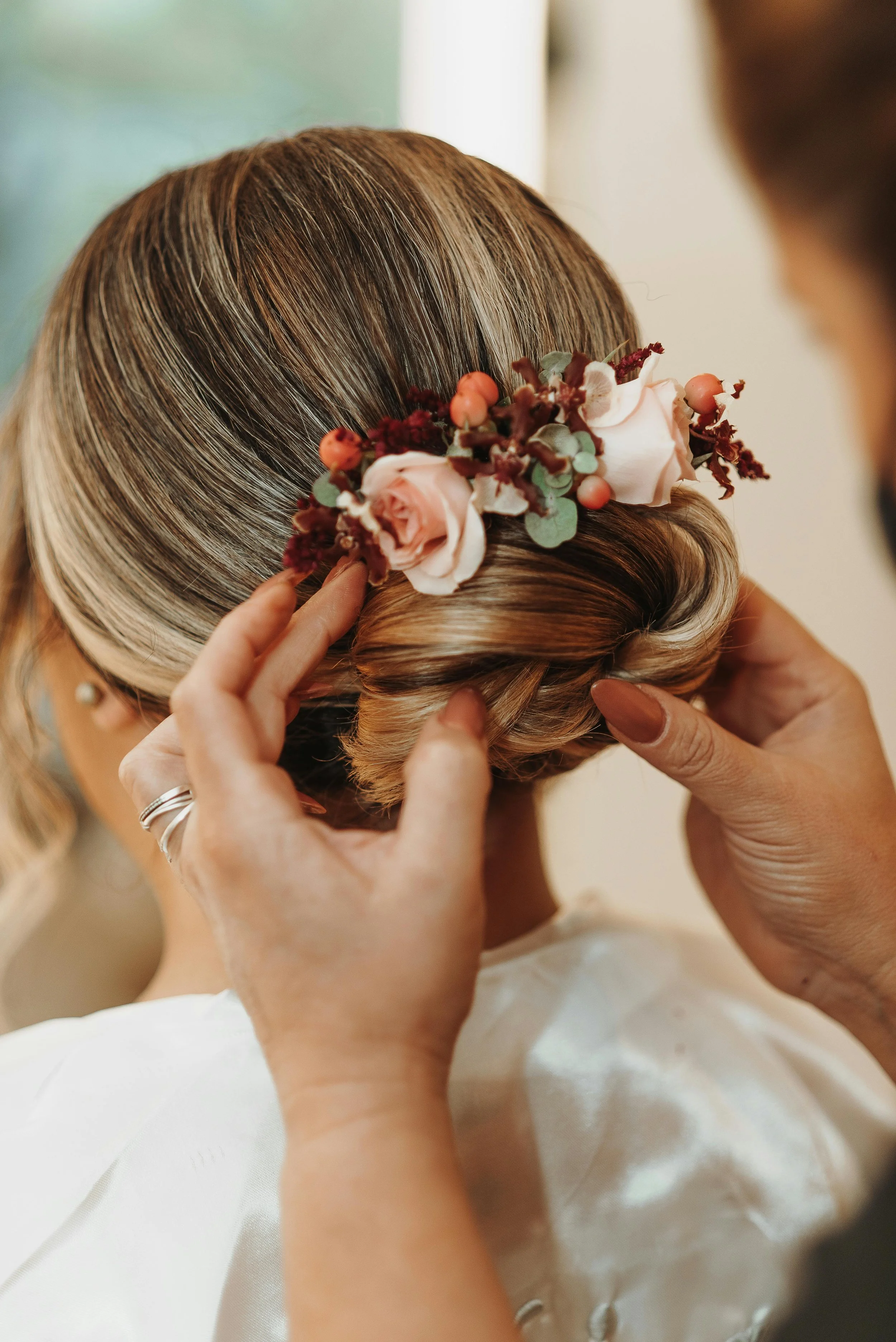 bride having her hair done in the morning with white and pink flowers