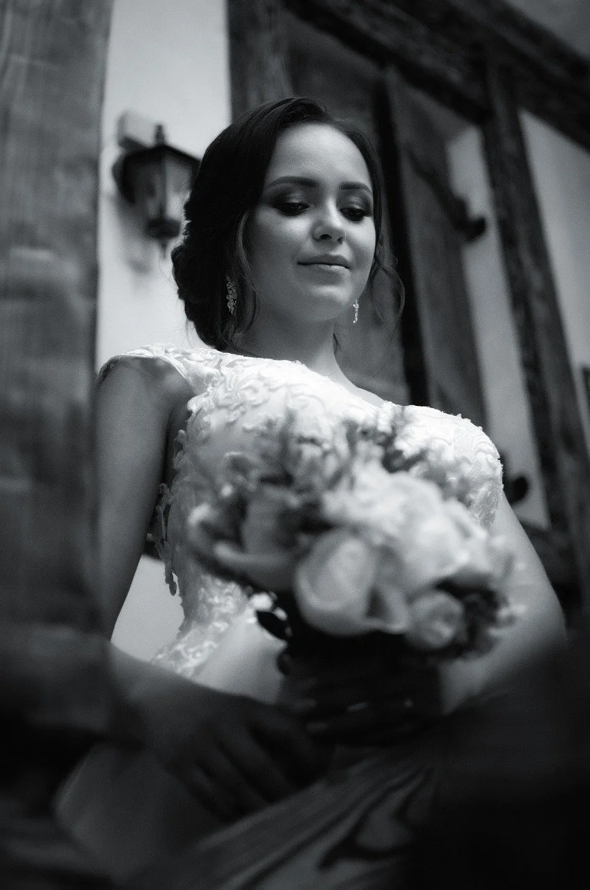 bride in black and white photo looking down at her wedding flowers