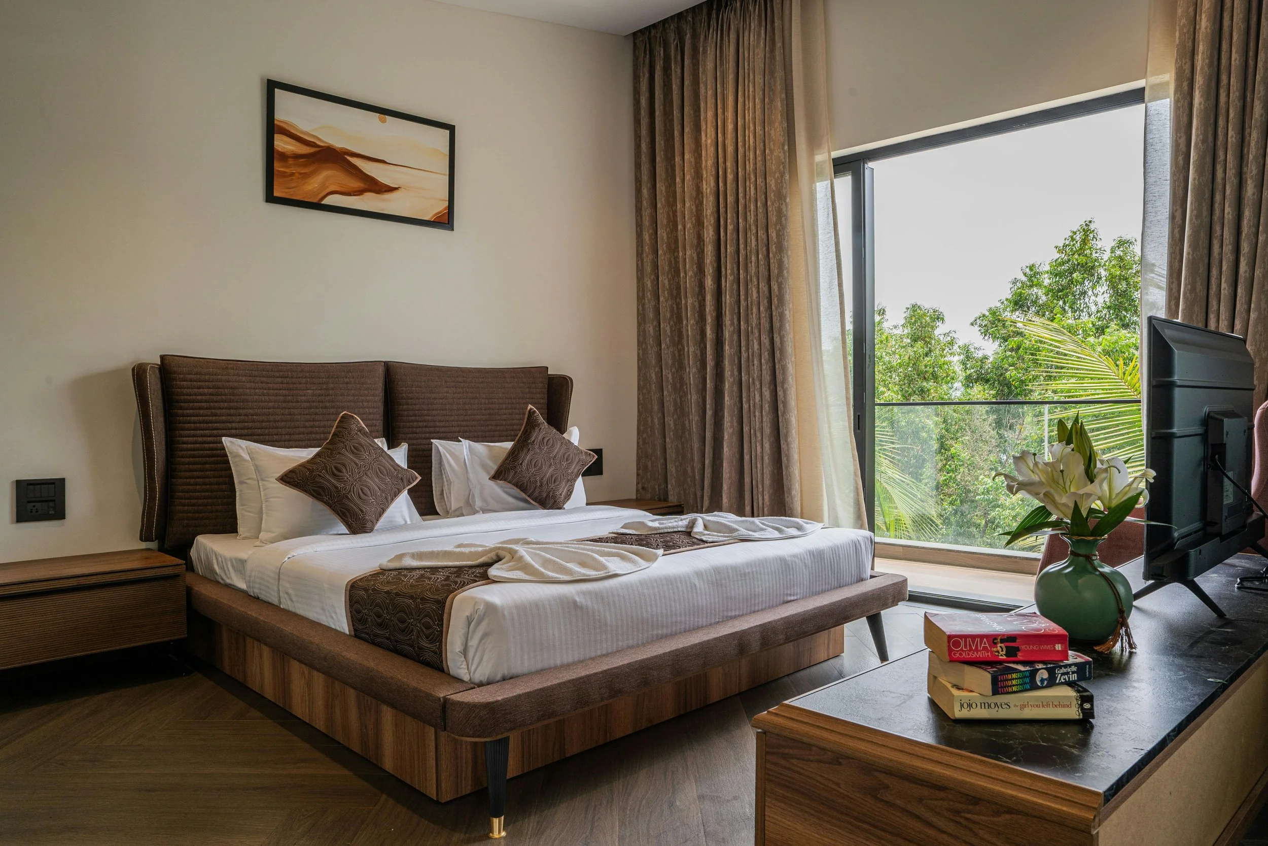 modern large bed facing in the middle of the room towards the TV with big window