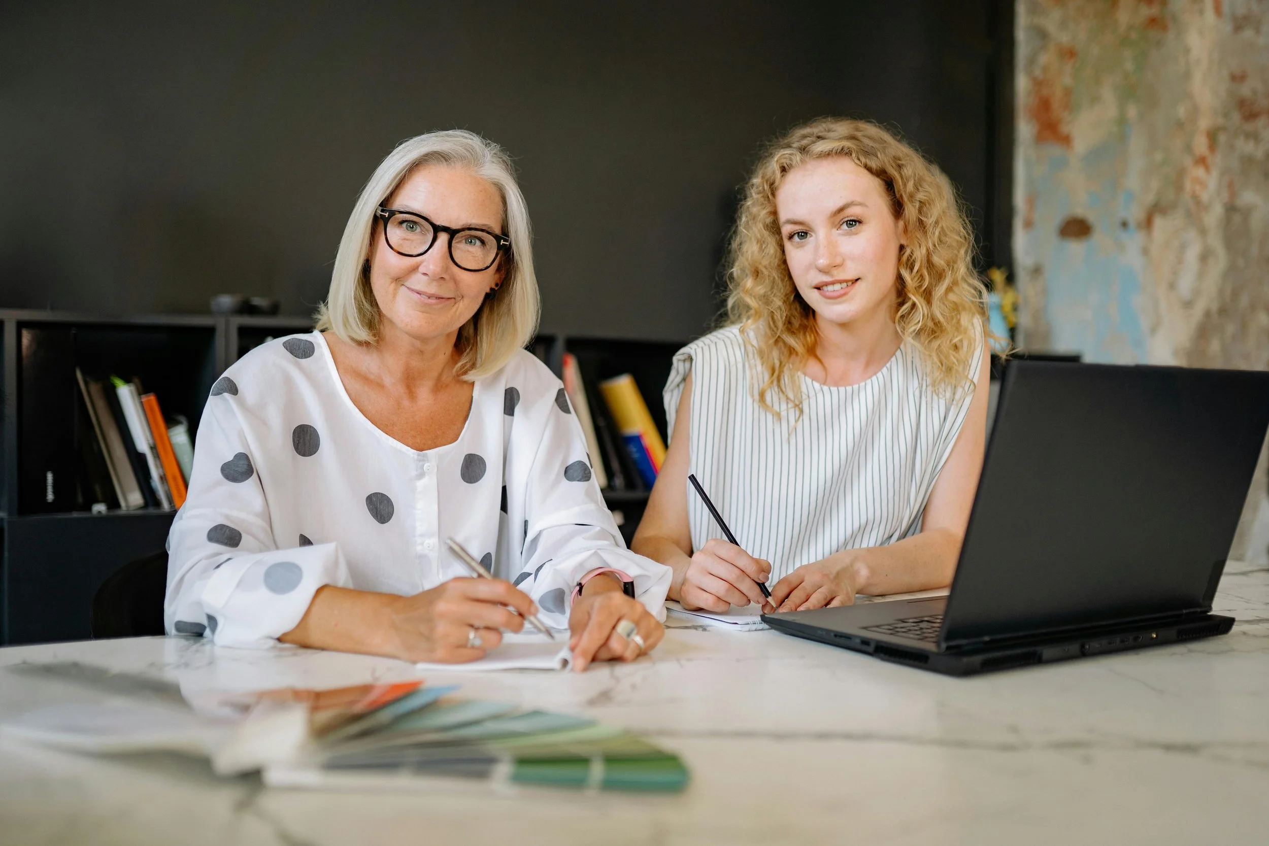 business owner and daughter sat together at desk looking at the camera smiling