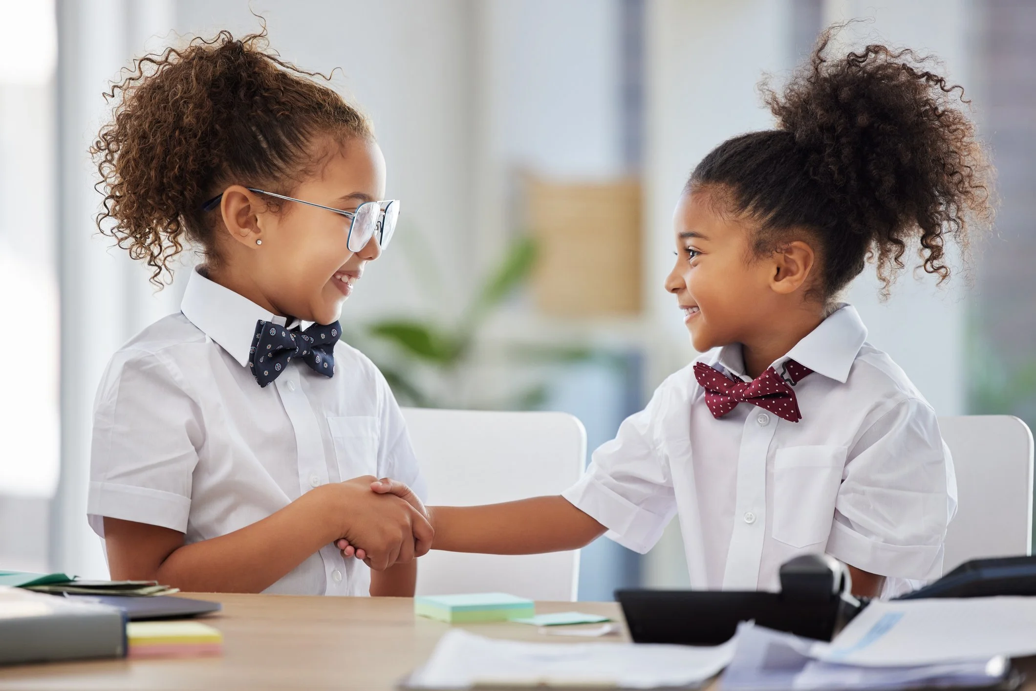 2 Happy girls wearing bow ties shaking hands