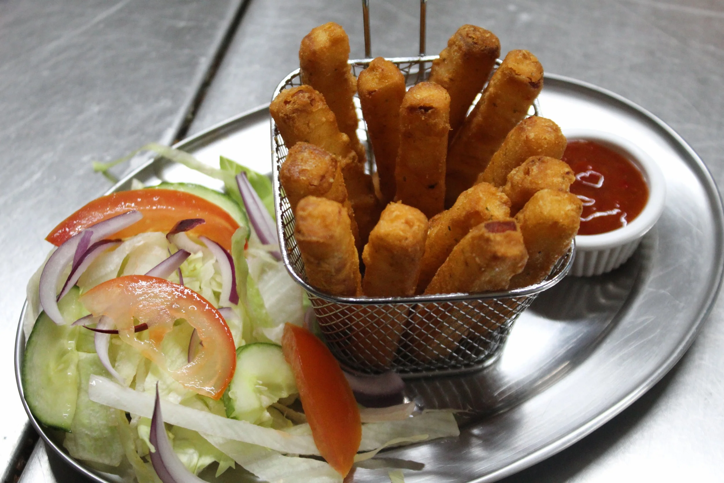 A serving of fried fish sticks with a side salad and a cup of ketchup.