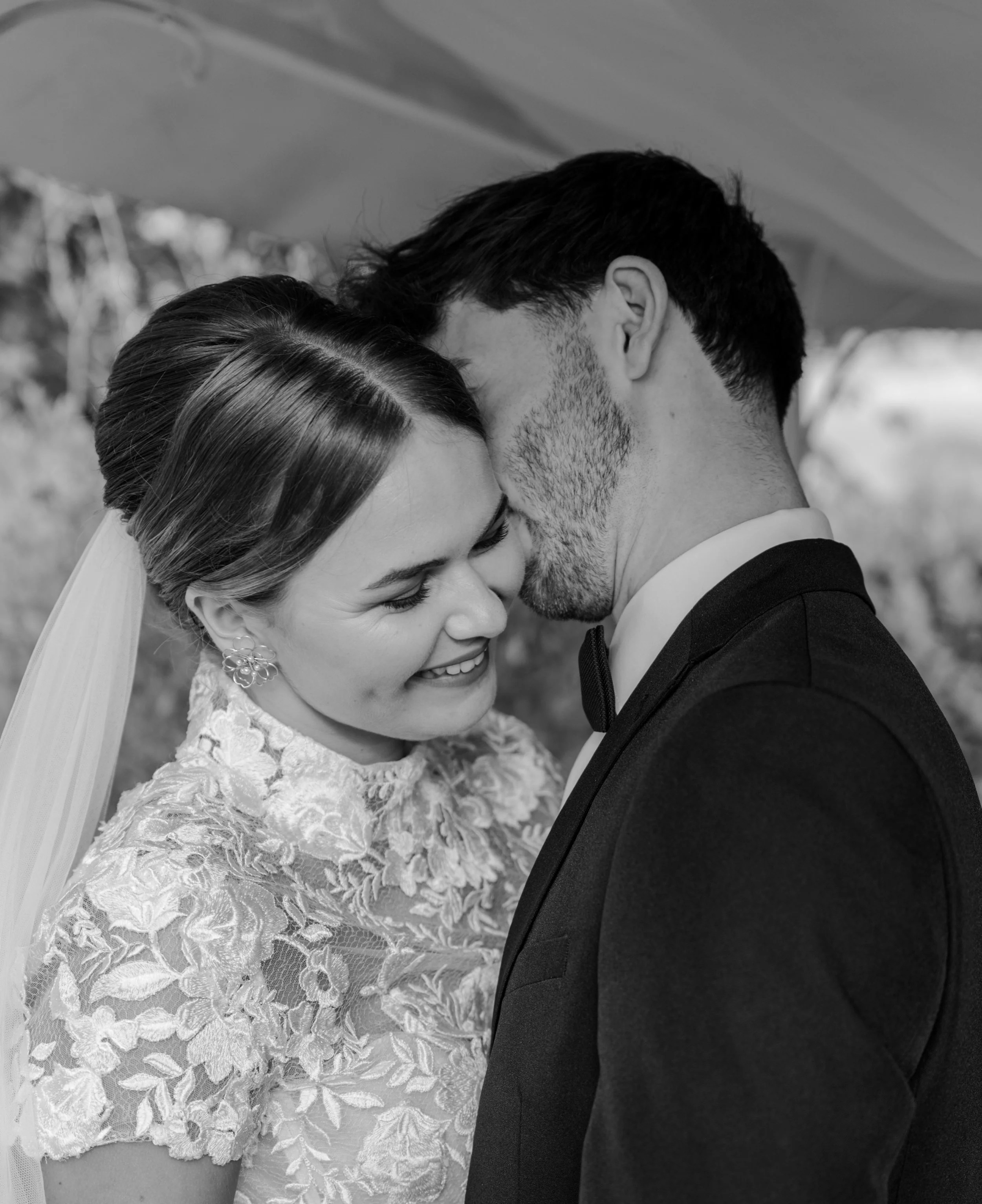 A black and white photo of a bride and groom smiling with their foreheads touching, celebrating their wedding. Styled shoot held at The Cheshire Venue planned by wedding planner Bootique Weddings and Events.