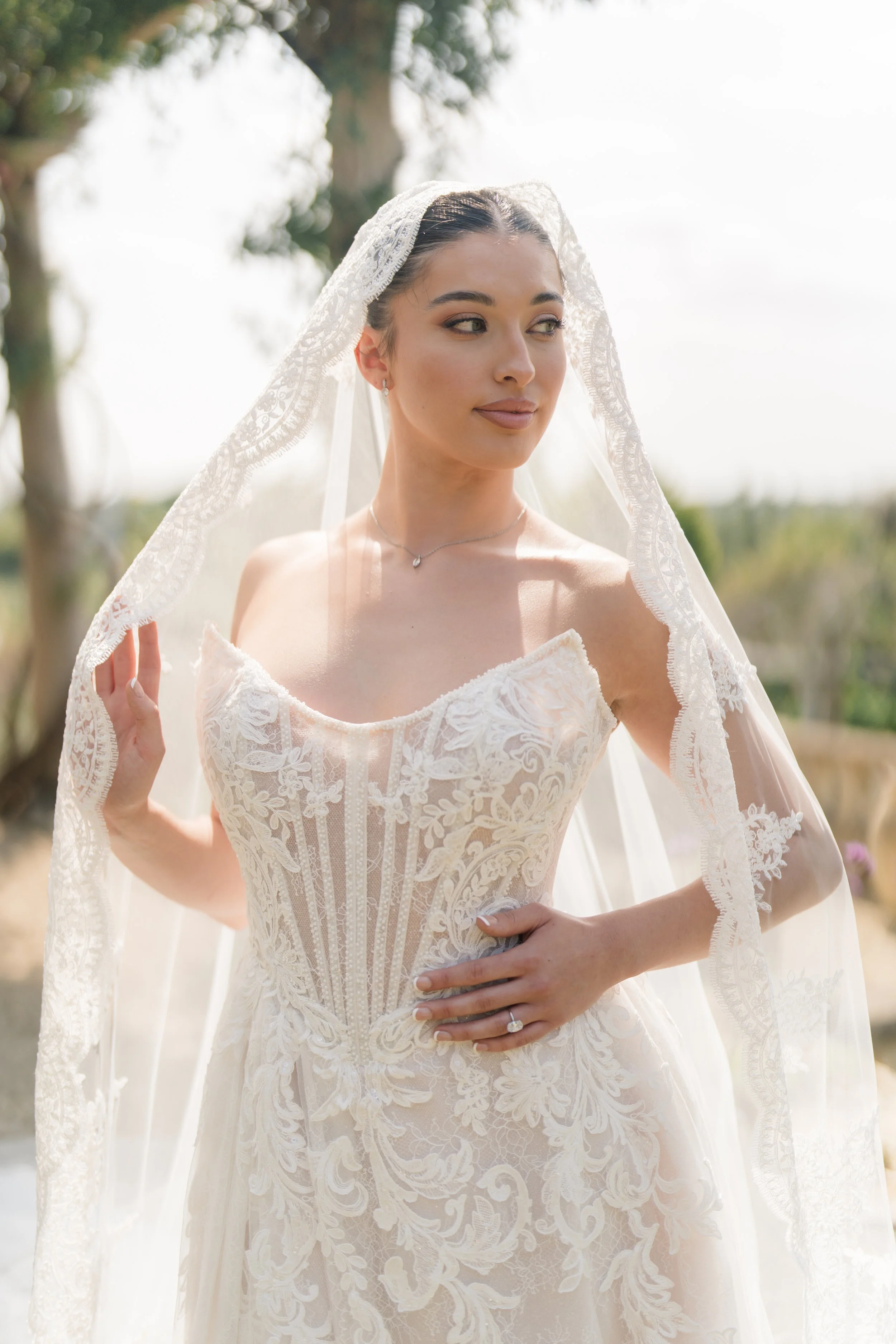 A woman wearing a wedding dress, veil, and jewelry outdoors on a sunny day. Styled shoot held at Euridge Manor assisted by Bootique Weddings and Events.