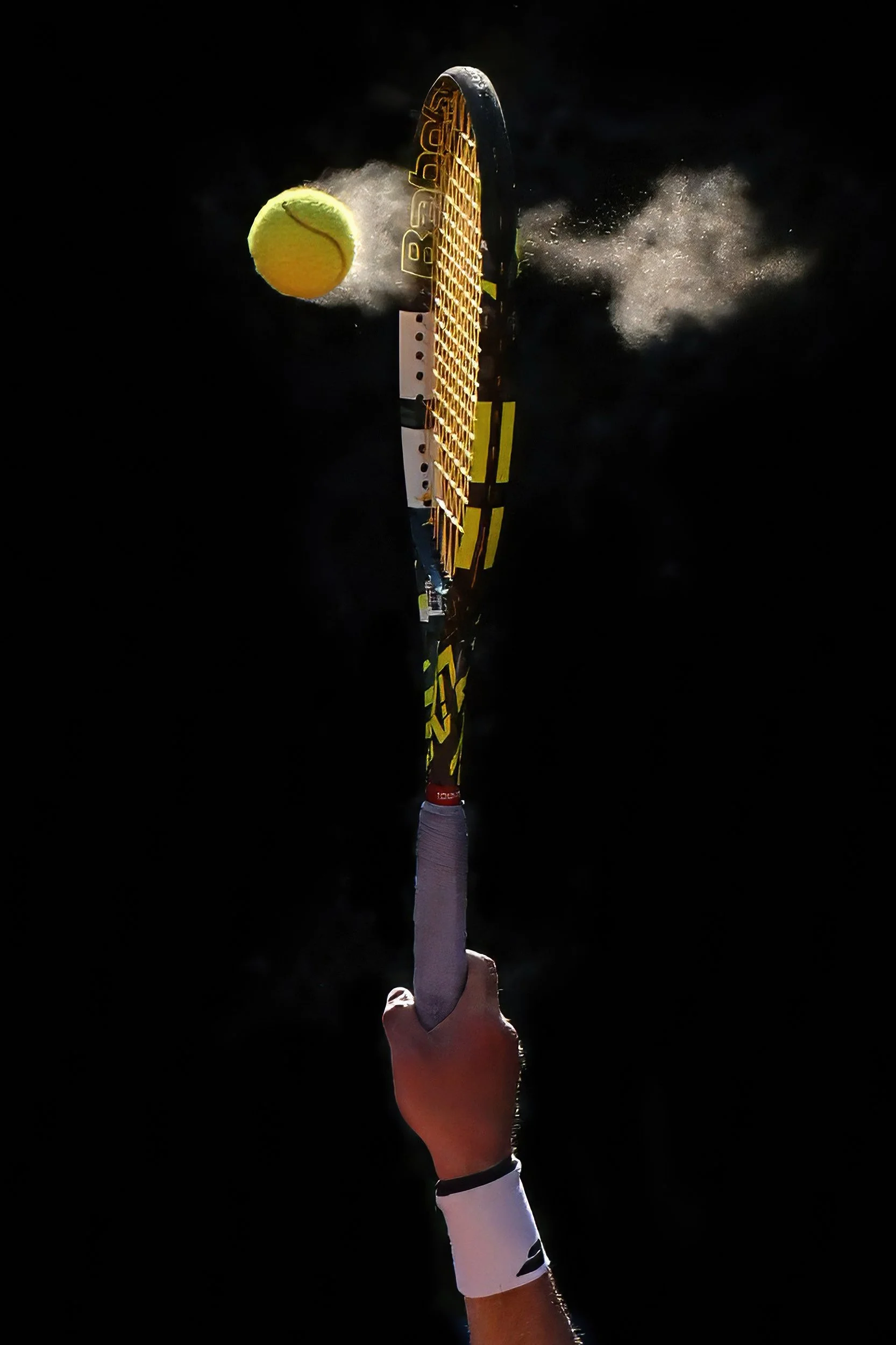 Une main tenant une raquette de tennis, frappant une balle de tennis jaune. La scène semble se dérouler dans l'obscurité ou avec un fond noir.