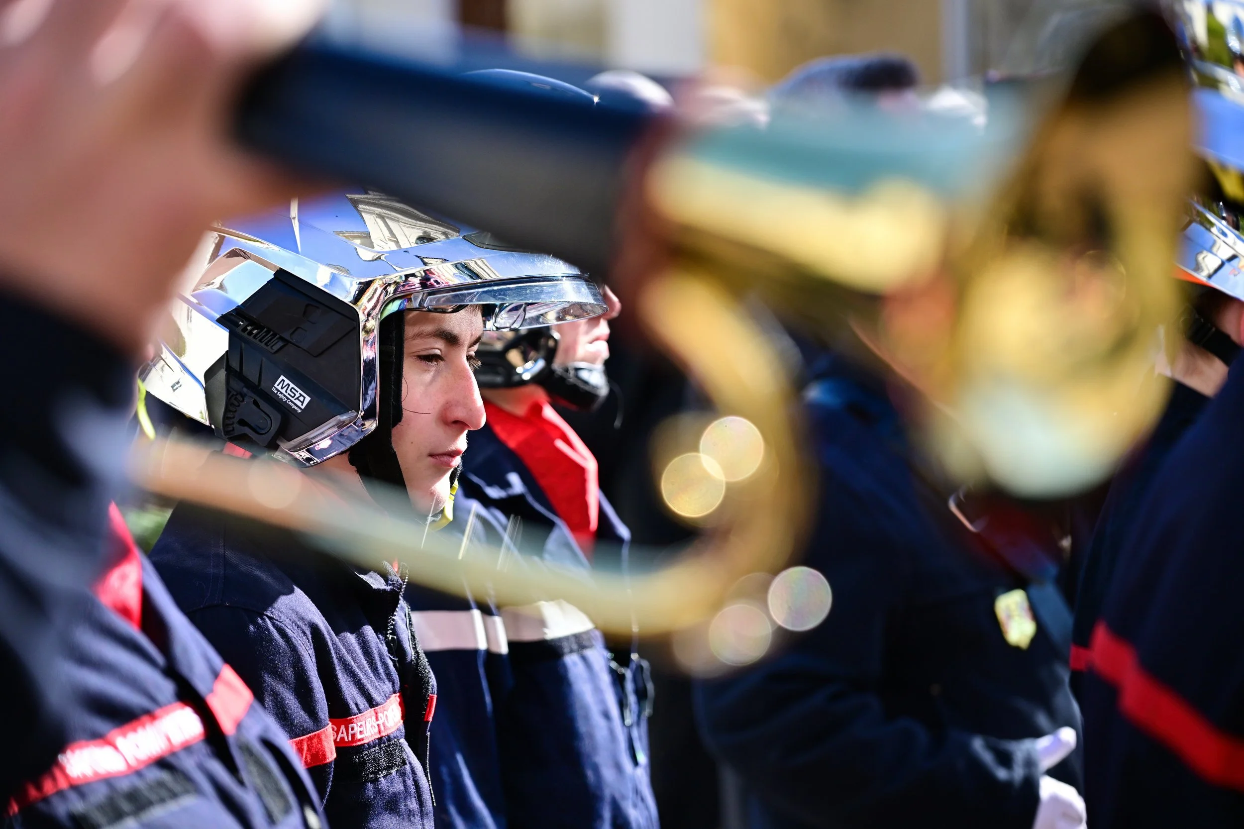 Groupe de personnes en uniforme portant casques de protection, probablement des pompiers ou des sauveteurs, debout en ligne.