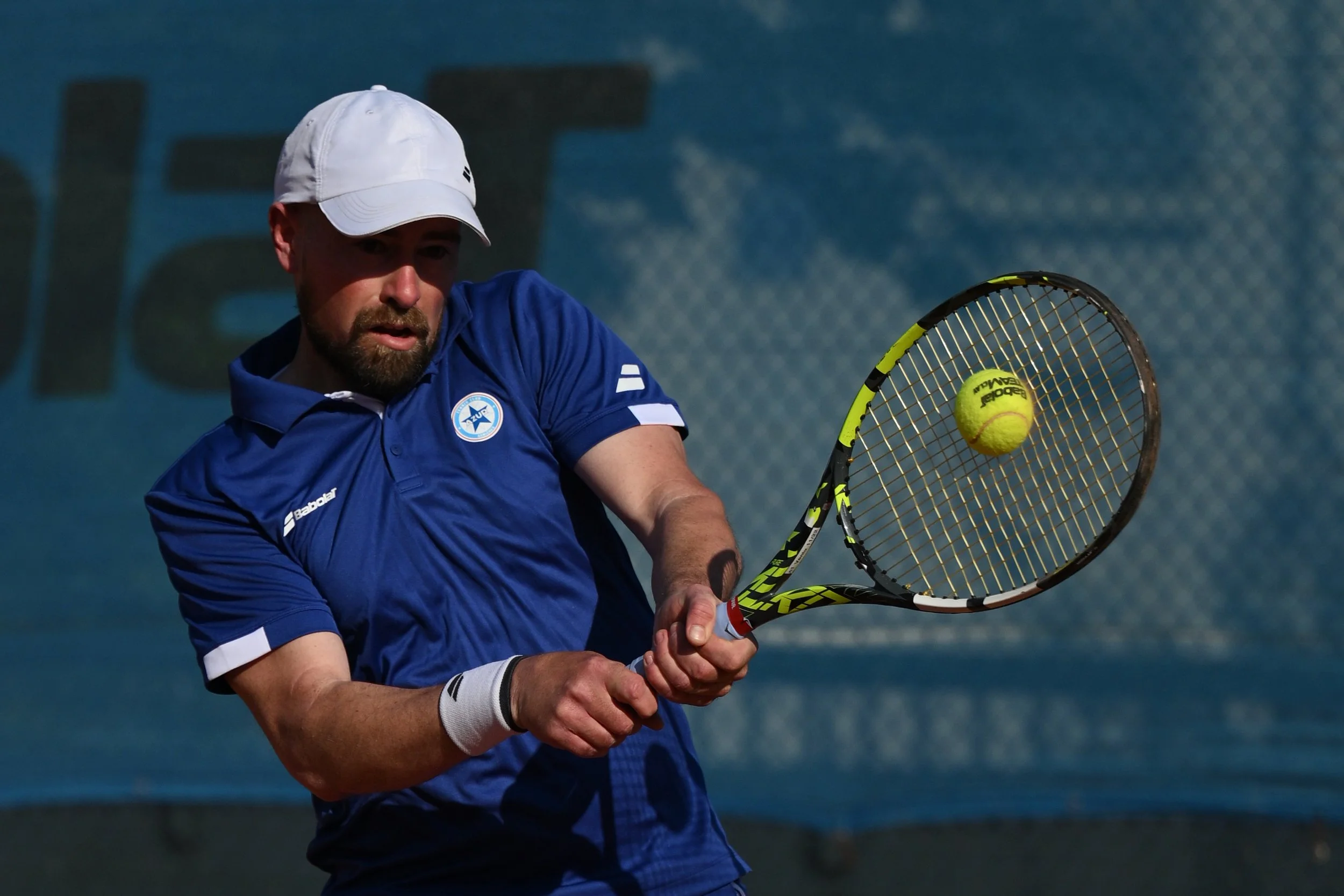 Un joueur de tennis en train de frapper une balle avec sa raquette sur un court en extérieur.