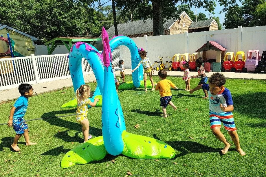 Children playing outdoors with inflatable water sprinckler.