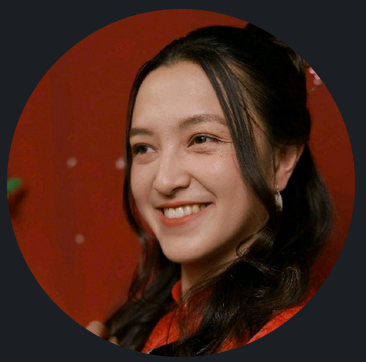 Jeune femme souriante avec des cheveux longs, portant une tenue rouge, fond rouge avec petits points blancs.