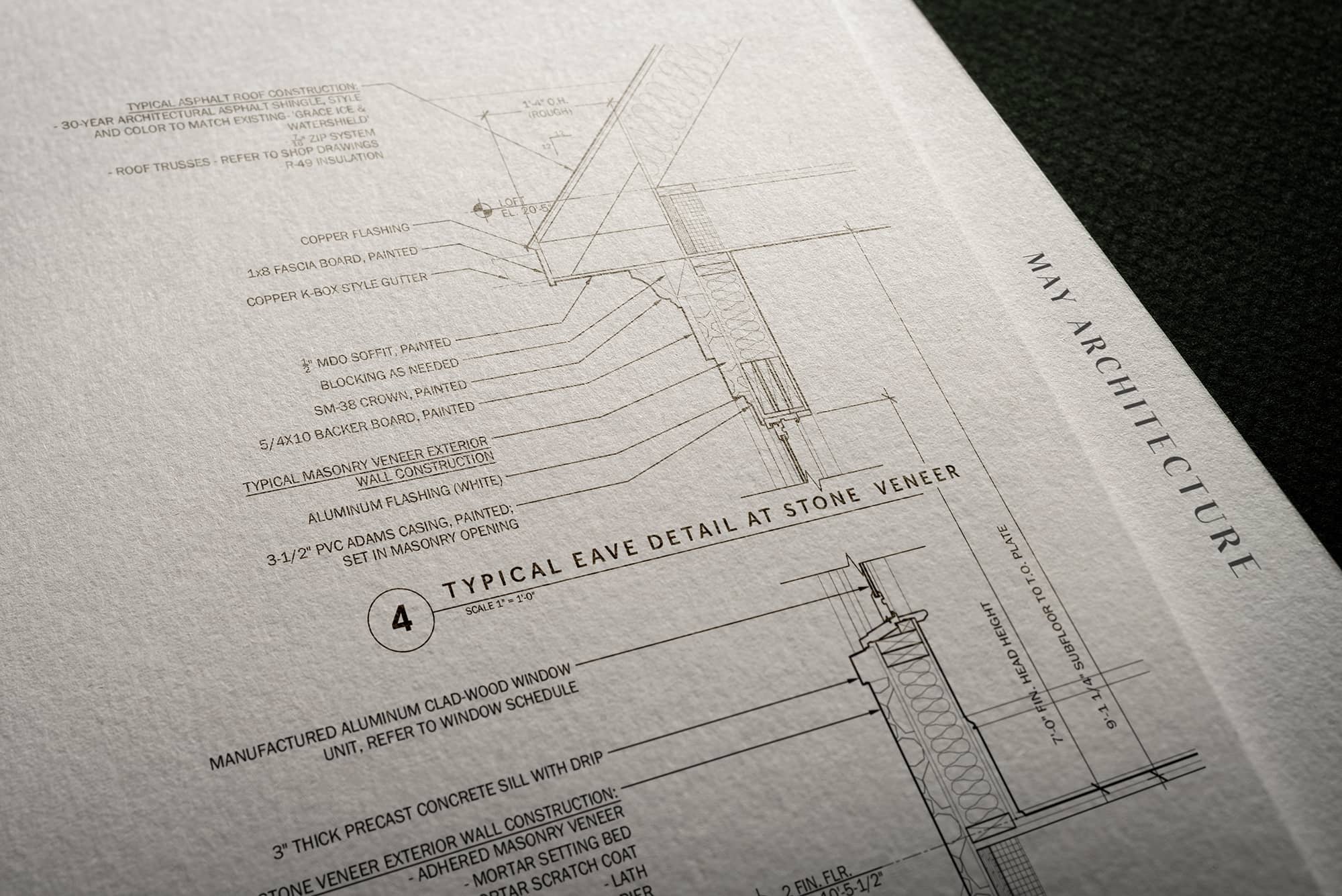 Close-up of an architectural blueprint detailing roof and wall construction at a stone veneer.