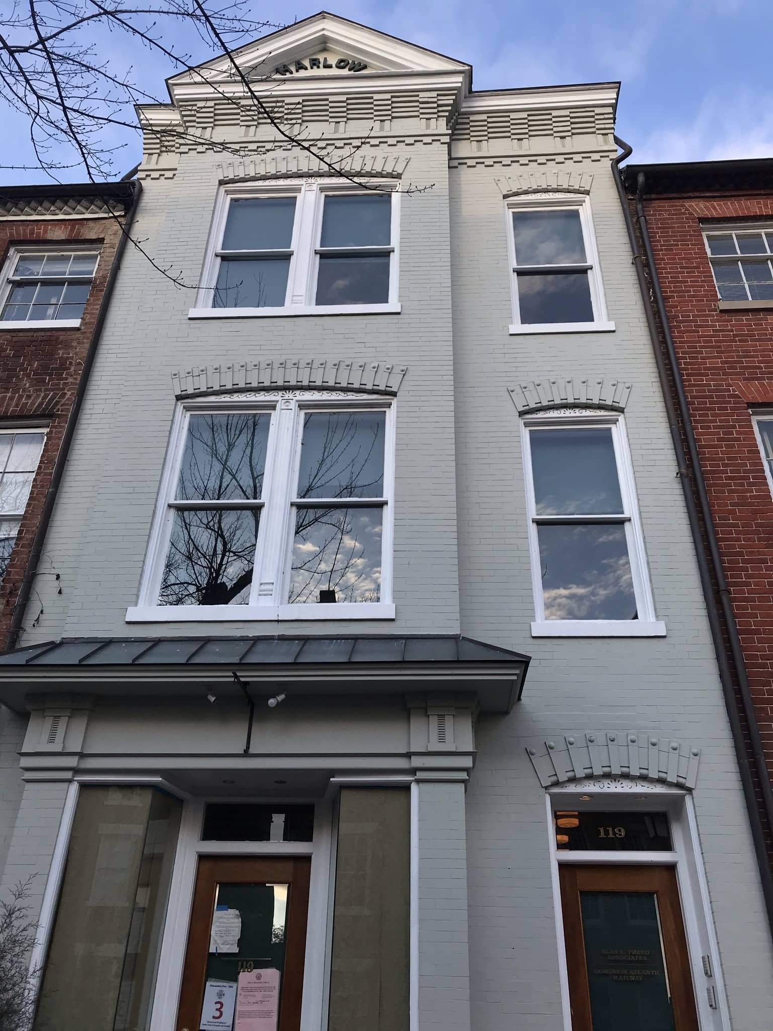 A three-story white brick building with decorative architectural details and large windows, located between two older brick buildings. The building has the name 'CHARLOW' at the top.