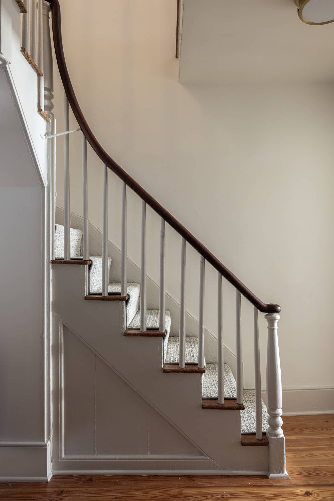 A staircase with white railings, wooden handrail, and carpeted steps in a home interior.