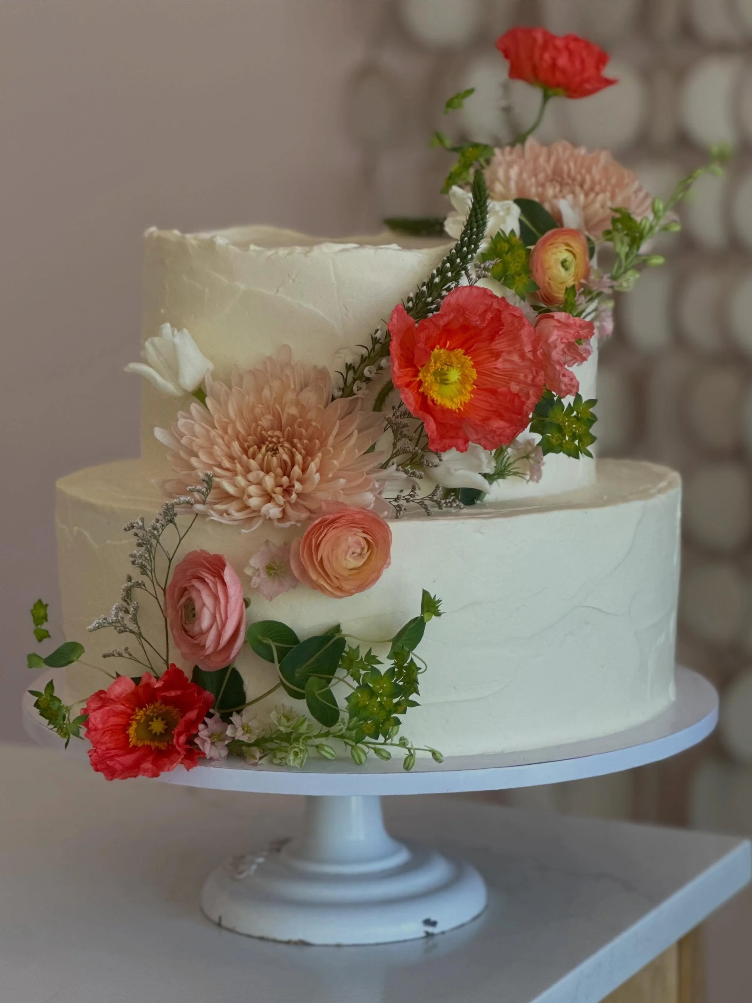 Lovelovelove these gorgeous blooms of poppy, ranunculus, frilly white tulips &amp; massive mums on our biggest yet 14&rdquo; tiered cake!💥 Thank you @woodstock.floraldesign you truly have the most special &amp; unique flowers to elevate our cakes. ?