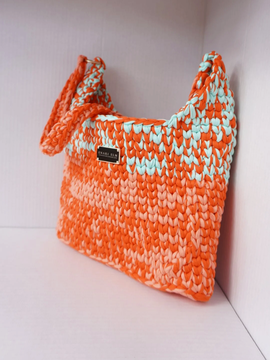 Hand-crocheted shoulder bag in orange, coral, and aqua with thick woven straps, measuring 32cm long, 6cm wide, and 33cm tall