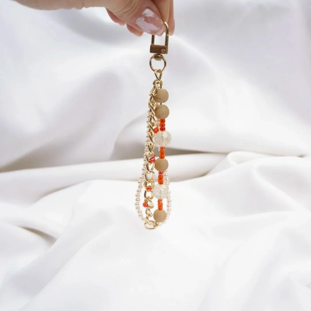 Handmade neutral beaded keychain with pearl beads and gold chain on white background