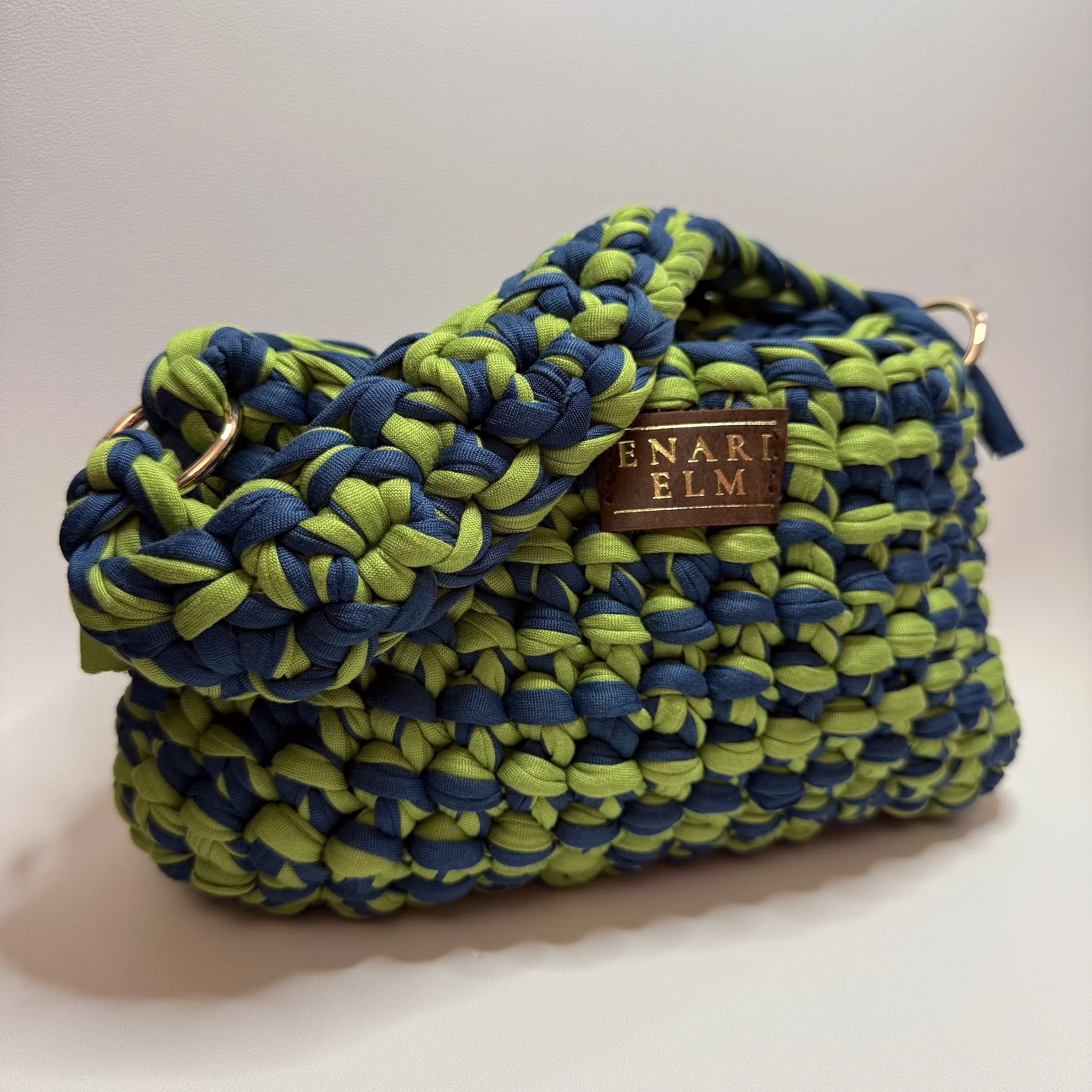 Hand‑crocheted bag in blue and lime green with ENARI ELM leather tag.