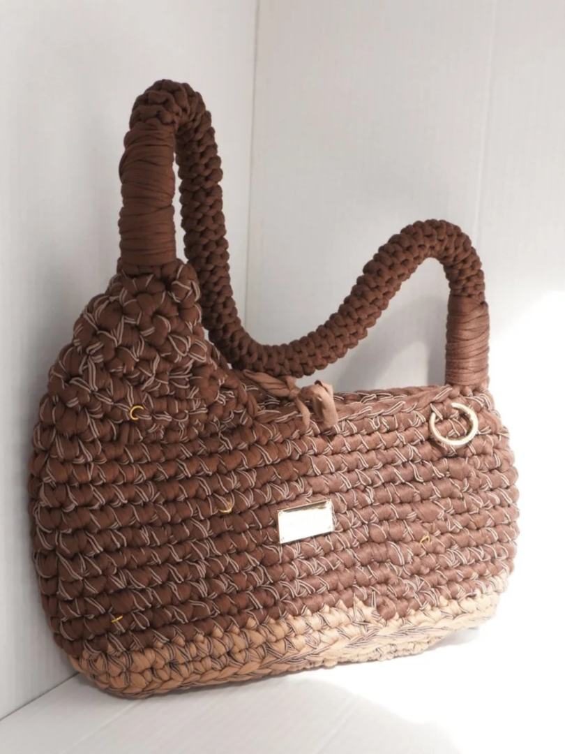 Hand-crocheted brown and tan shoulder bag with textured stitching and gold ring details on a white background