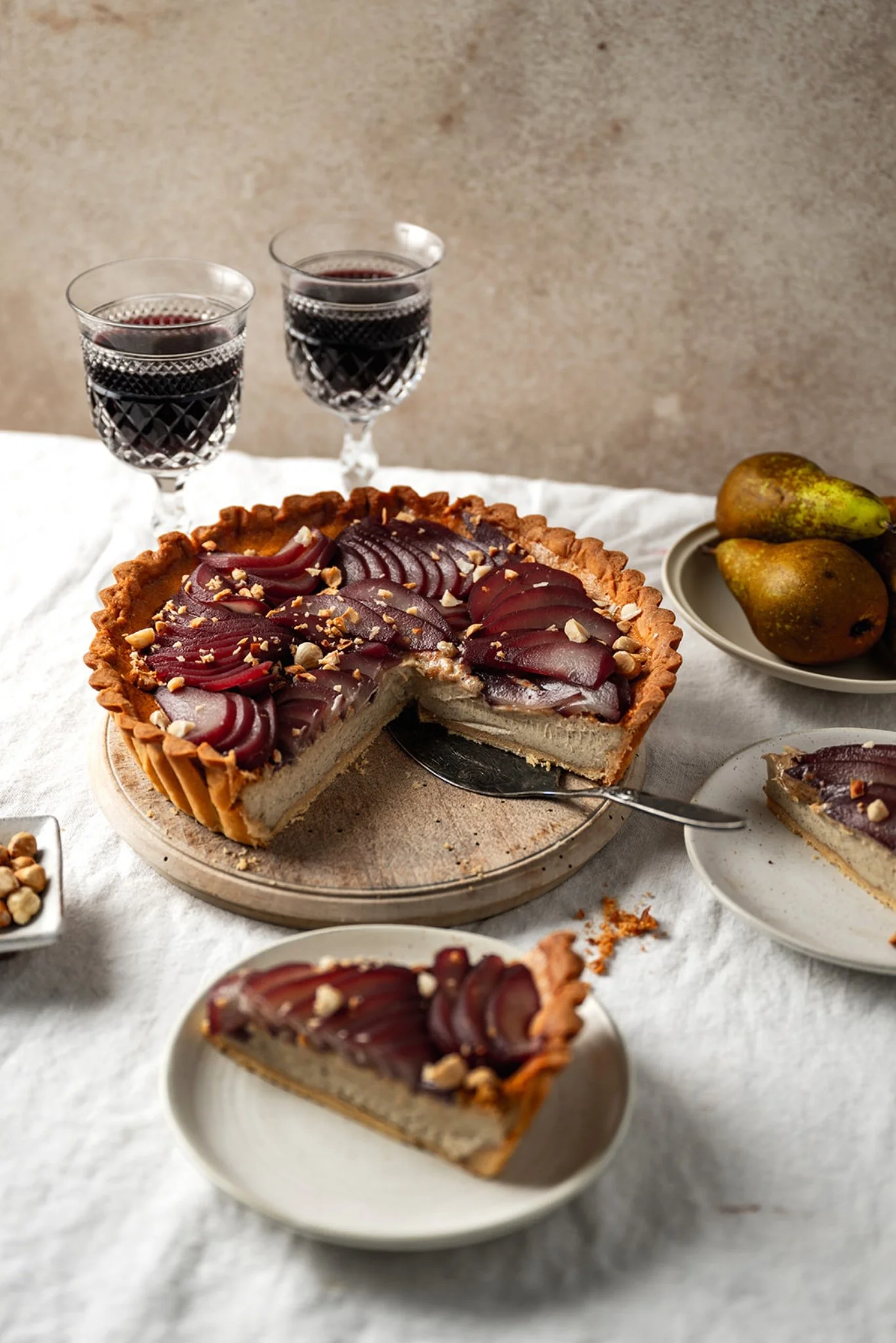 Spiced pear custard tart with fanned poached pears on top, glossy and ruby stained from red wine