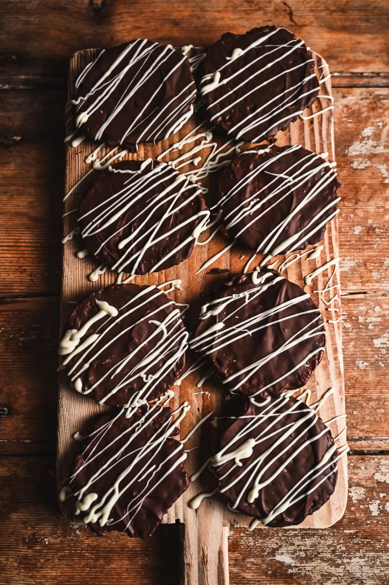 Overhead view of florentines on a rustic board showing white chocolate drizzle pattern over dark chocolate