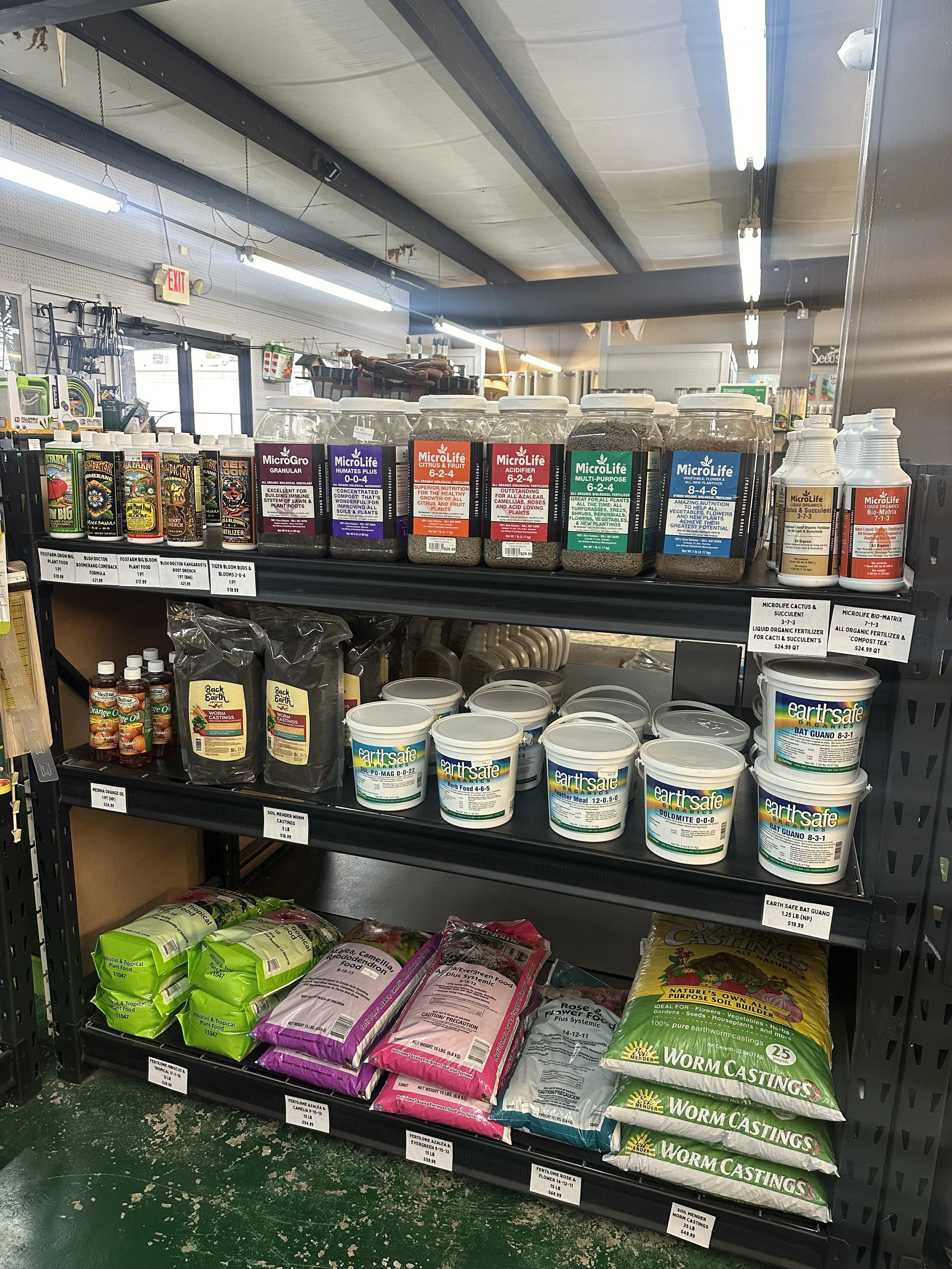 Well-organized fertilizer shelf in a garden center, showing clear merchandising with neatly arranged and labeled garden care products.