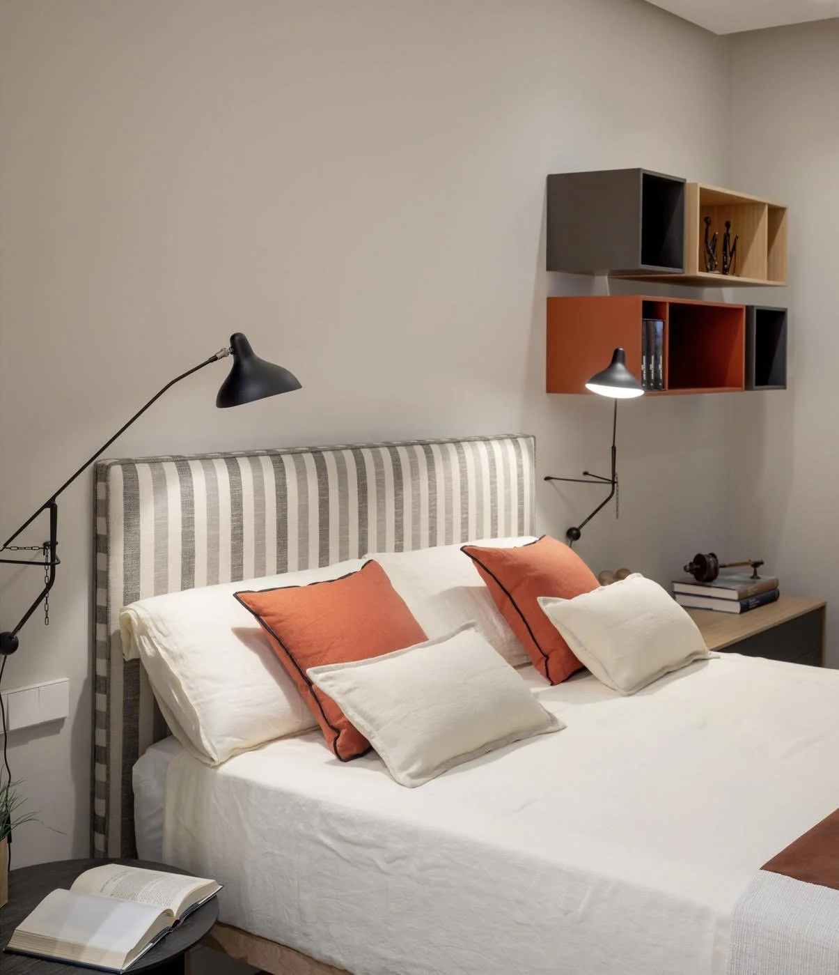 Dormitorio con cabecero de rayas y detalles en tono naranja en piso reformado en Barrio Salamanca