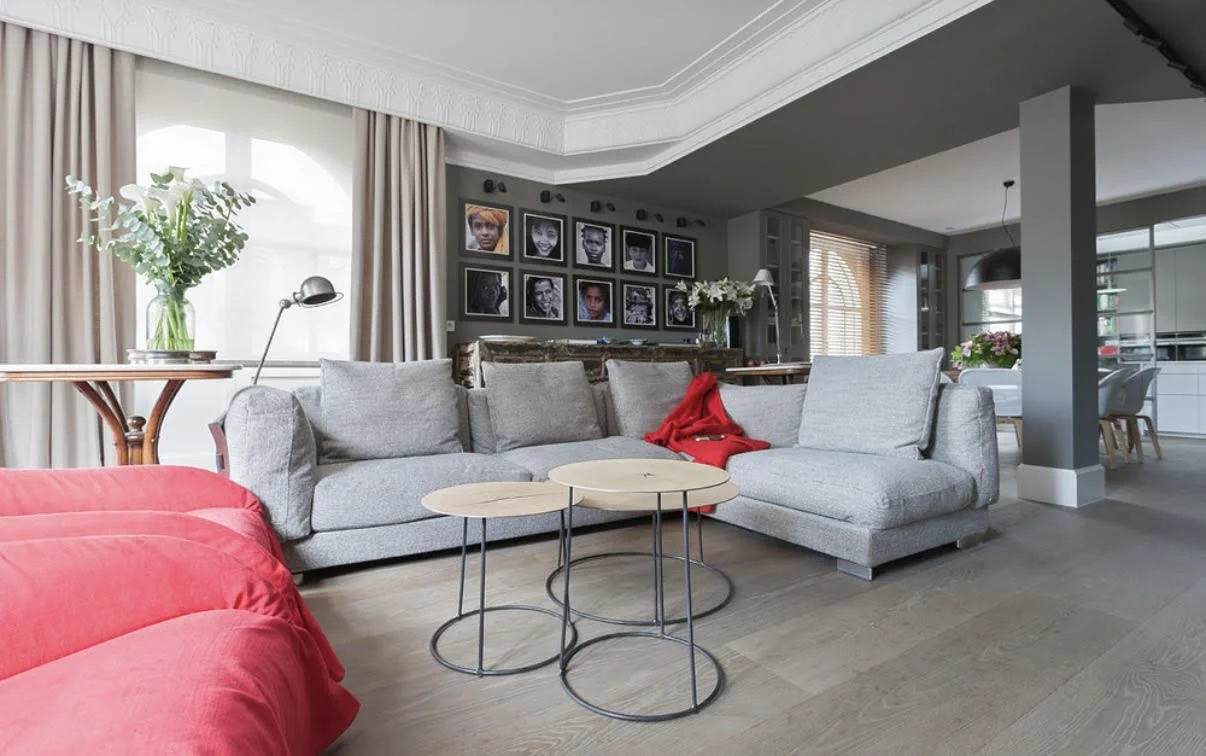 Sala de estar con mobiliario en tonos rojos y estantería a medida en piso reformado en Barrio Salamanca