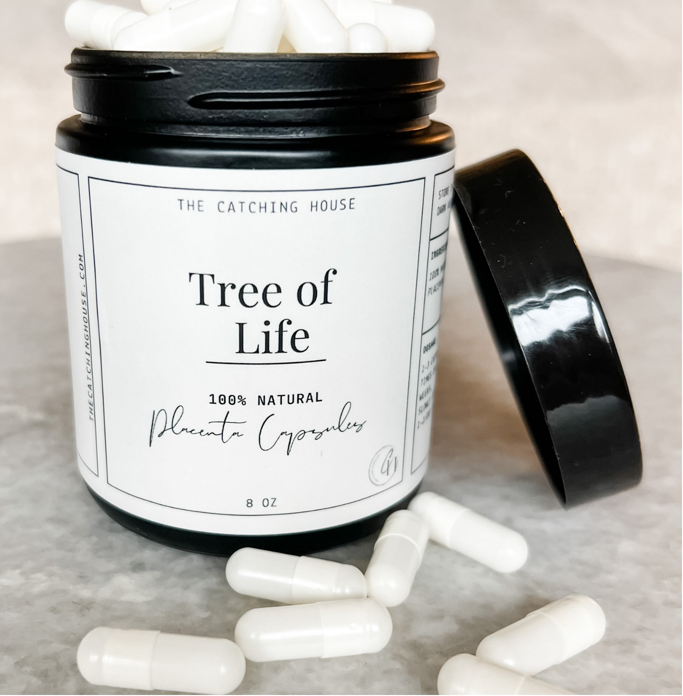 An open black container labeled "Tree of Life" with white capsules spilling out, on a light surface.