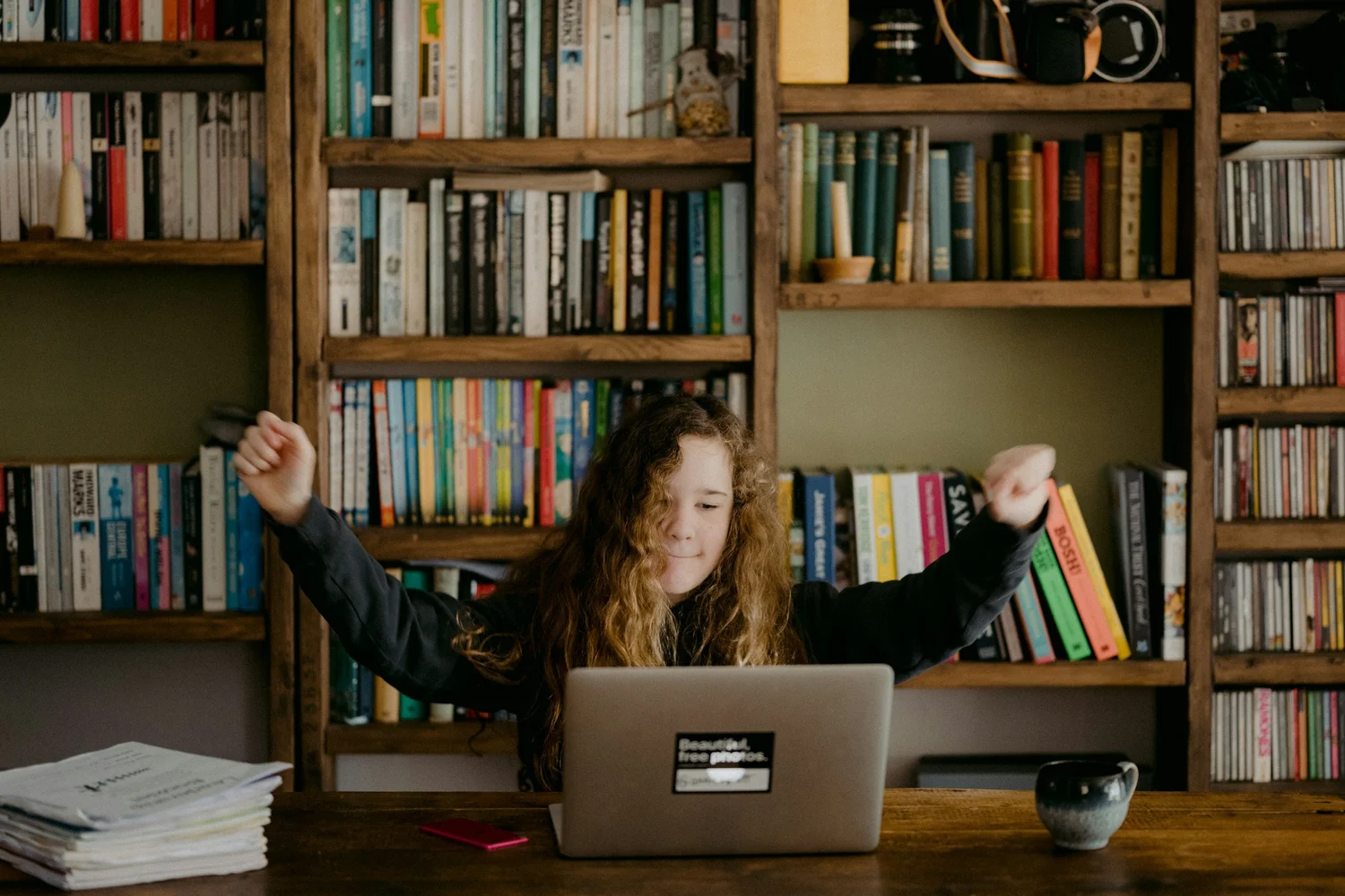 Child at a laptop raising hands in the air