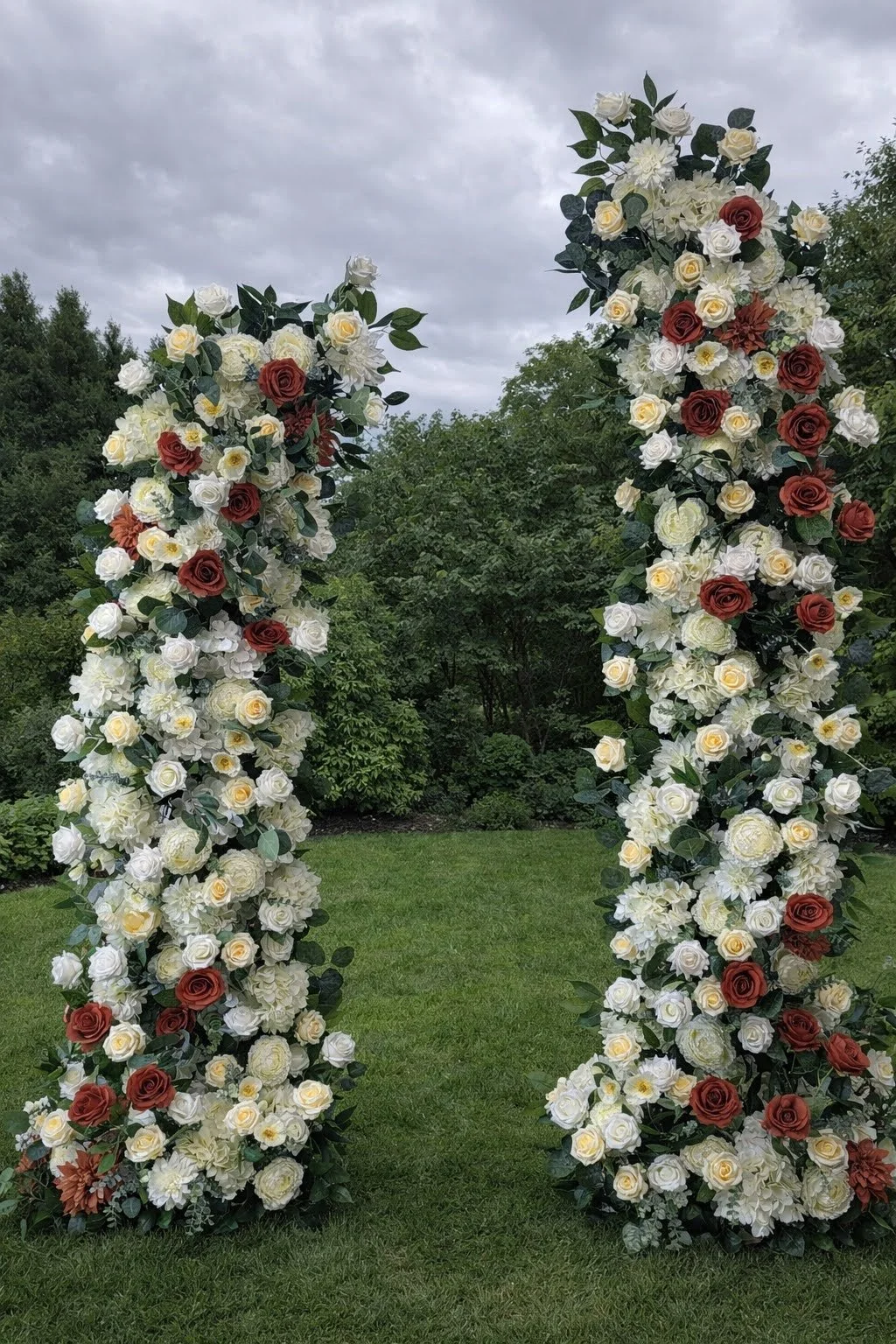 Wedding ceremony setup with floral arch, wooden barn doors, string lights, and candles along the aisle.