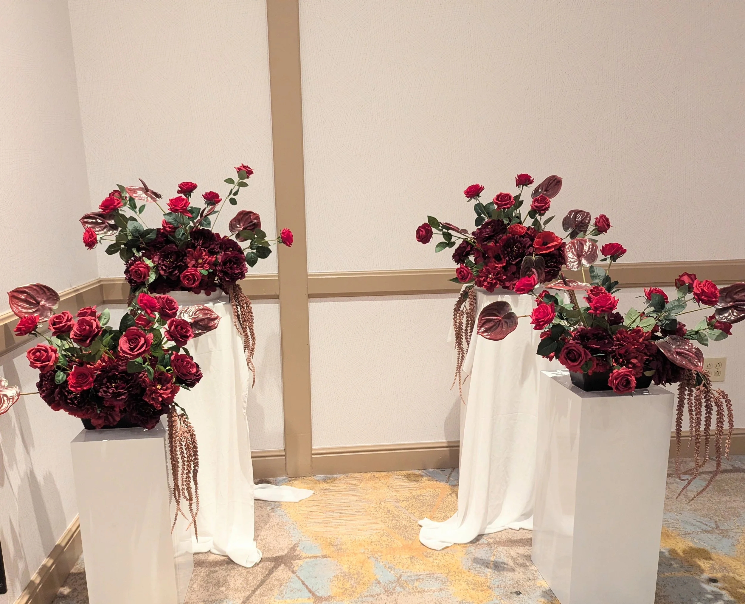 A flower arrangement with white, red, and brown flowers, including roses and hydrangeas, in a black vase.