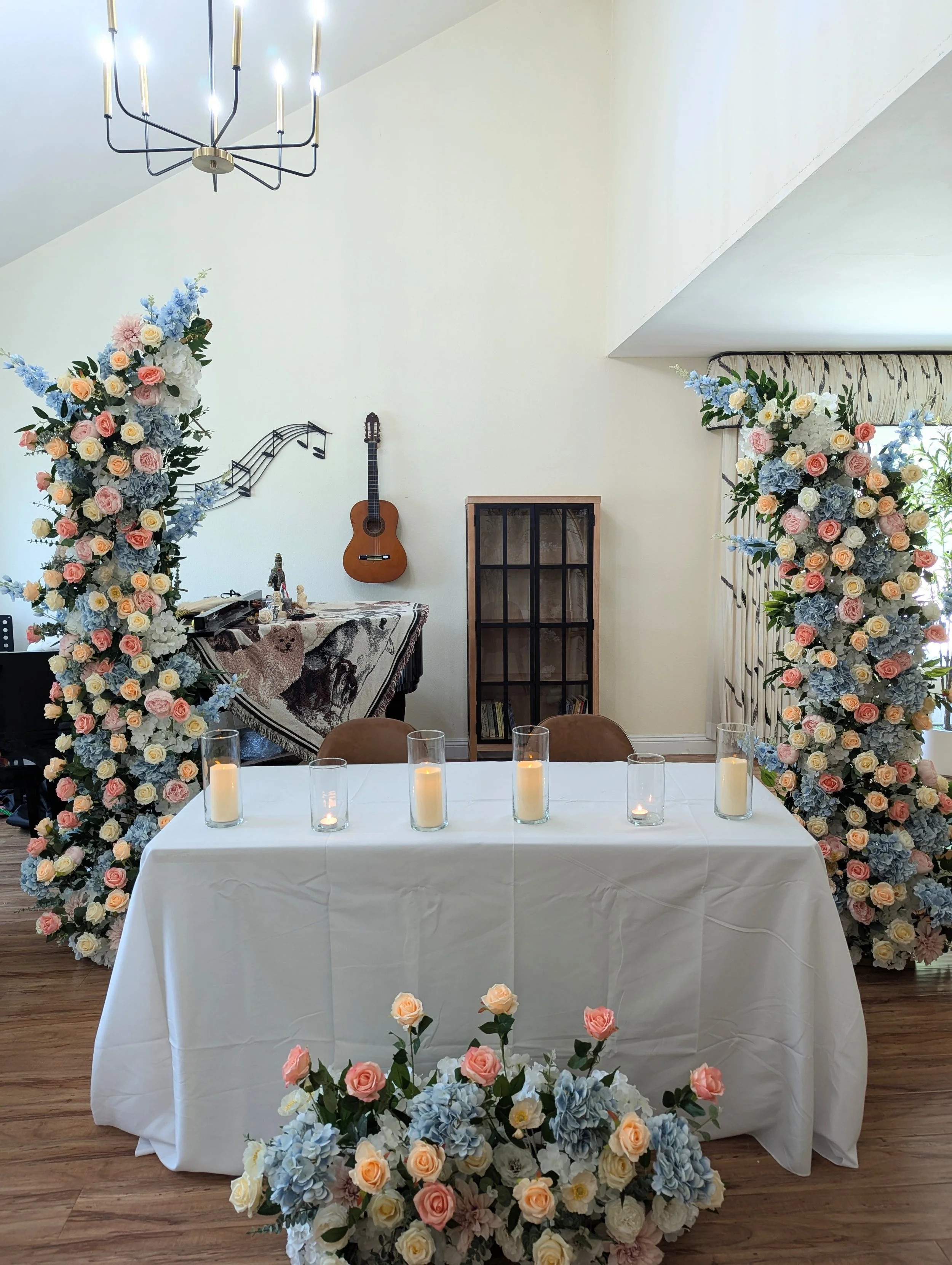 Two large floral archways with pink, peach, white, and blue flowers, flanking a tall mirror with gold trim and Eiffel Tower decoration, at a wedding venue.