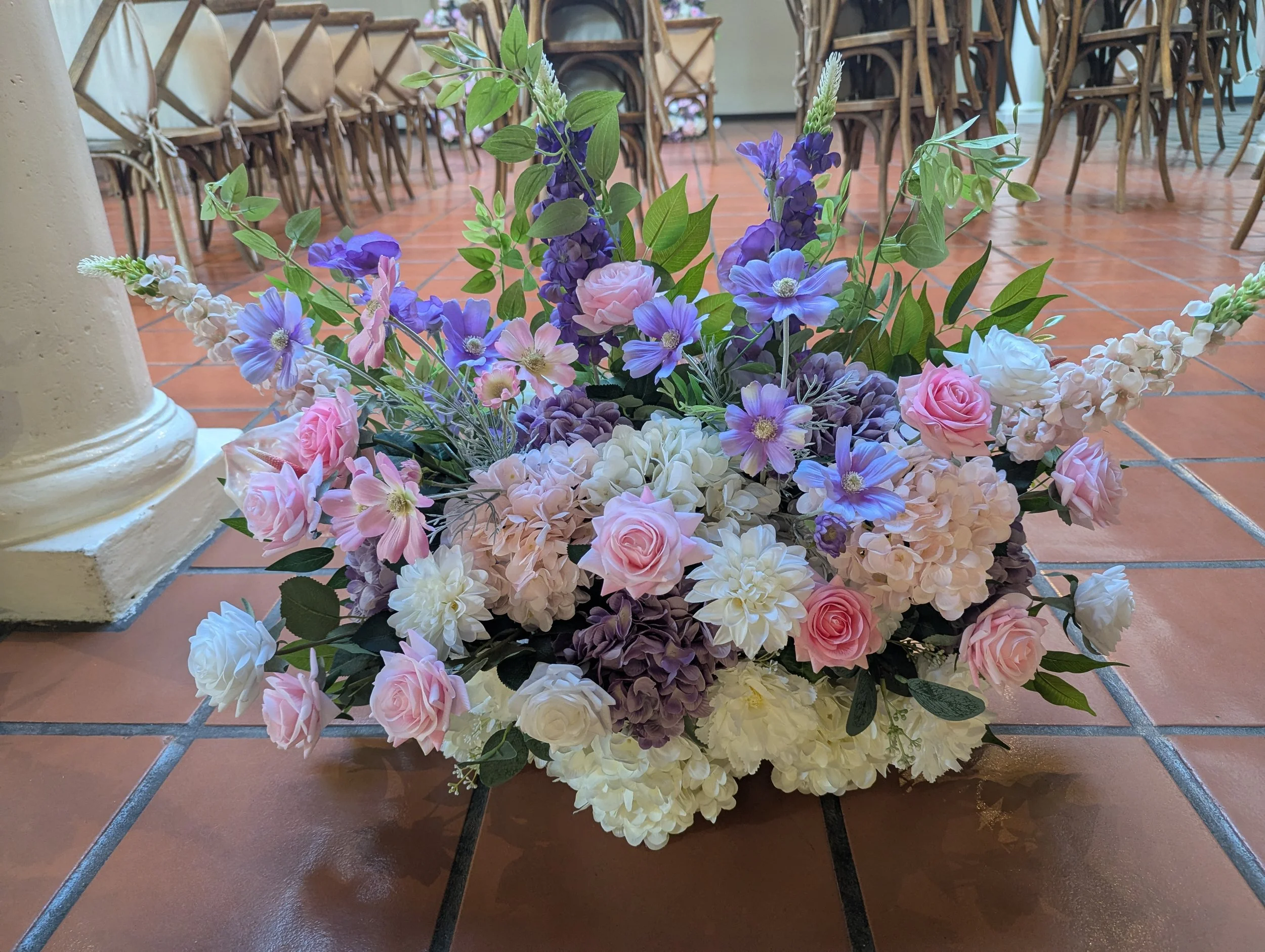 A colorful arrangement of pink, purple, and white flowers with green leaves, with a SoCal flower studio logo at the bottom.
