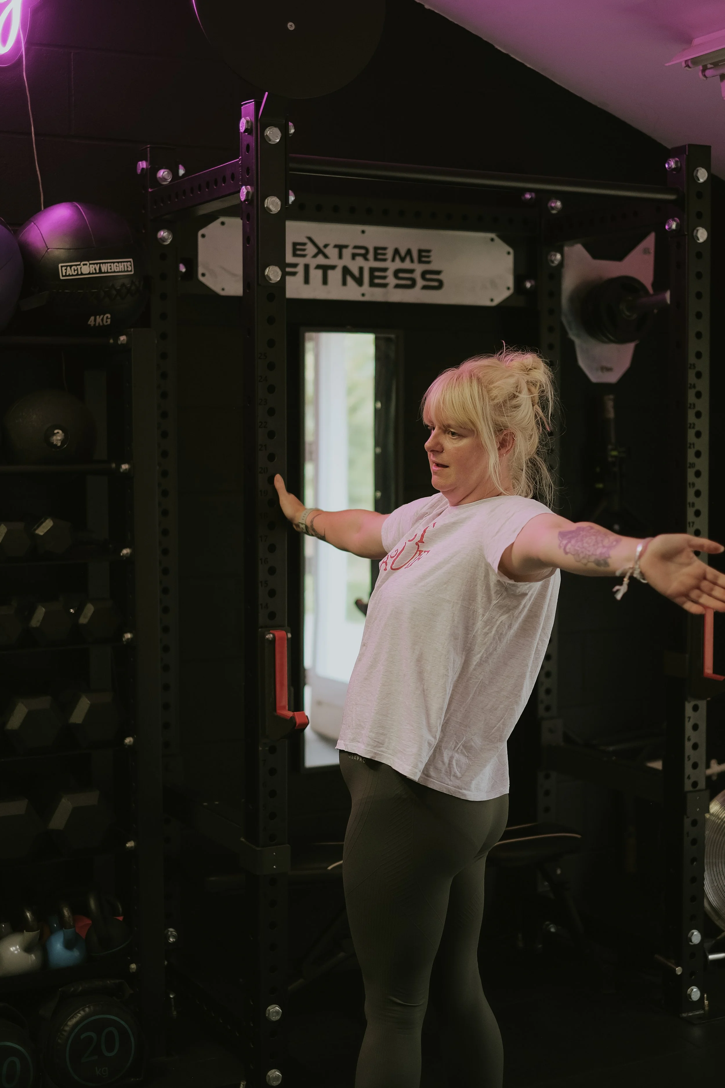 The Wholesome Movement gym with an open door, green wooden shutters, a tree in the foreground, and a grassy area.