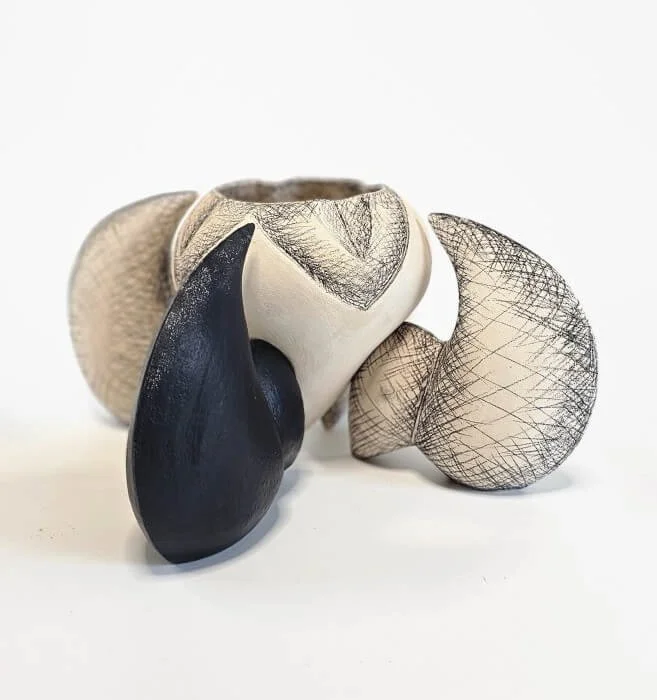 Abstract ceramic sculptures resembling organic shapes, with black, white, and textured surfaces.