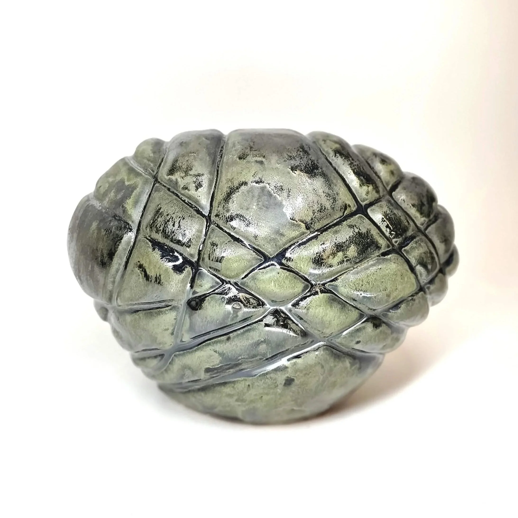 Mirsini Roumelioti. Mirsini Ceramics. Asphyxia. Hugs. Close-up of a metallic pine cone ornament with a shiny surface, set against a plain white background.