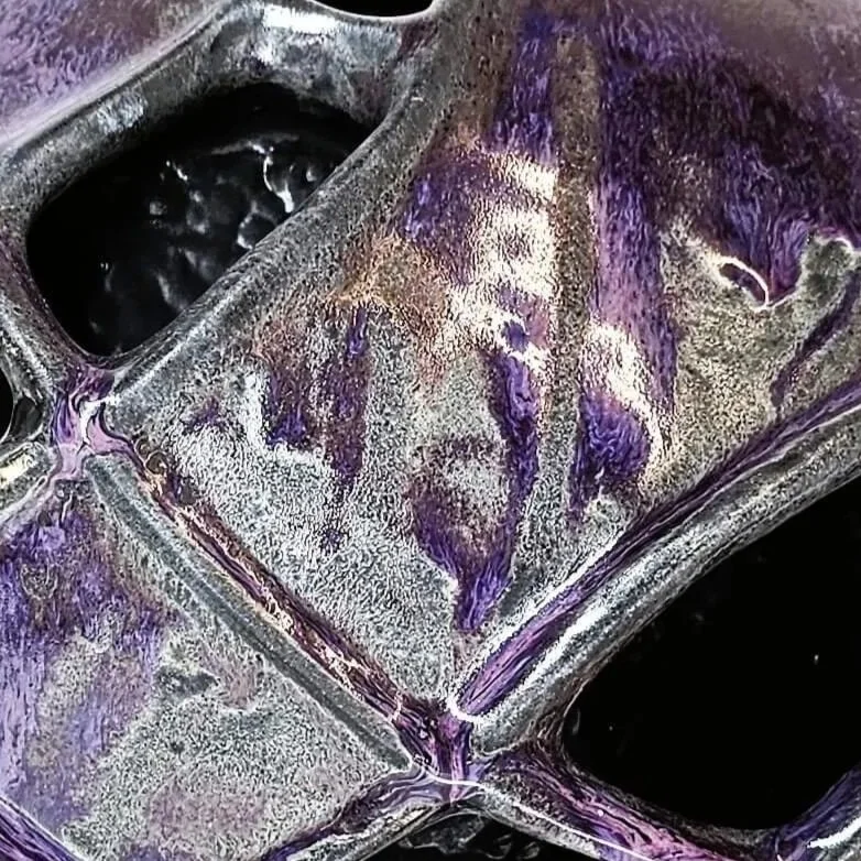 Mirsini Roumelioti. Mirsini Ceramics. Armor. Hugs. A decorative ceramic sculpture with a geometric, open lattice pattern in shades of purple, black, and metallic silver.